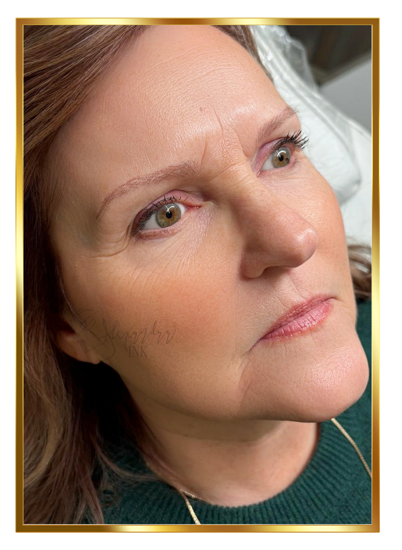Close-up of a middle-aged woman with light skin, brown hair, and green eyes, lying down with a neutral expression, wearing a green top and a gold necklace.