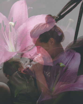 A woman and a child interacting with a large pink lily flower.