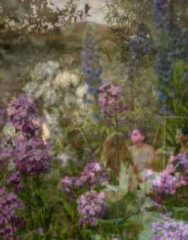 People gathered outdoors among purple and lavender flowers in a garden setting.