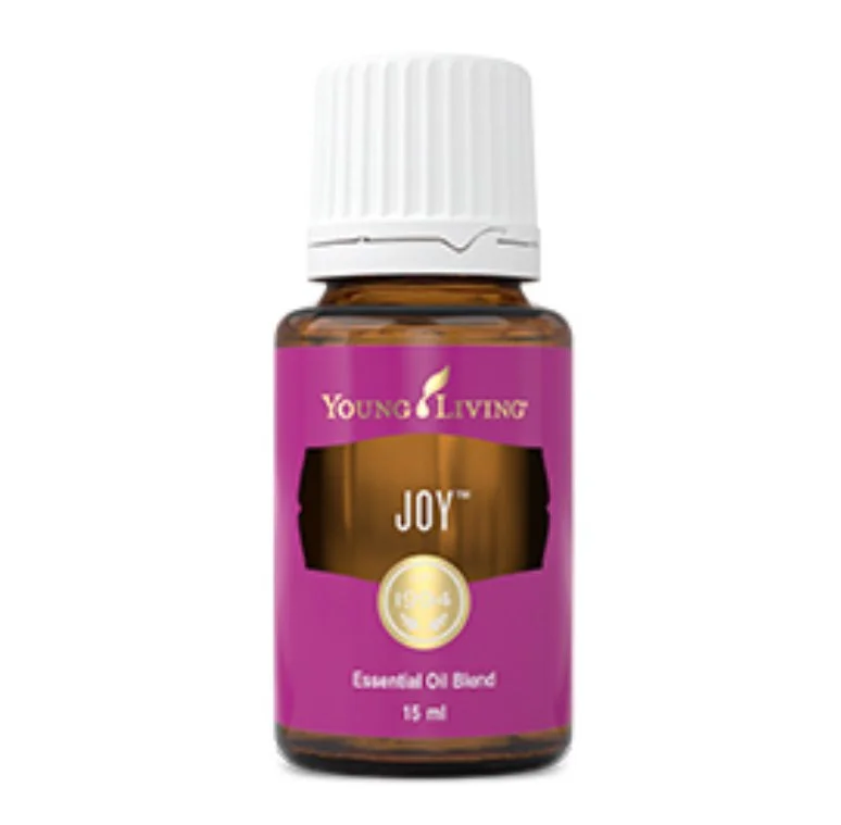 A small amber glass bottle labeled "JOY" Young Living essential oil blend, with a white ribbed cap, and a purple label.