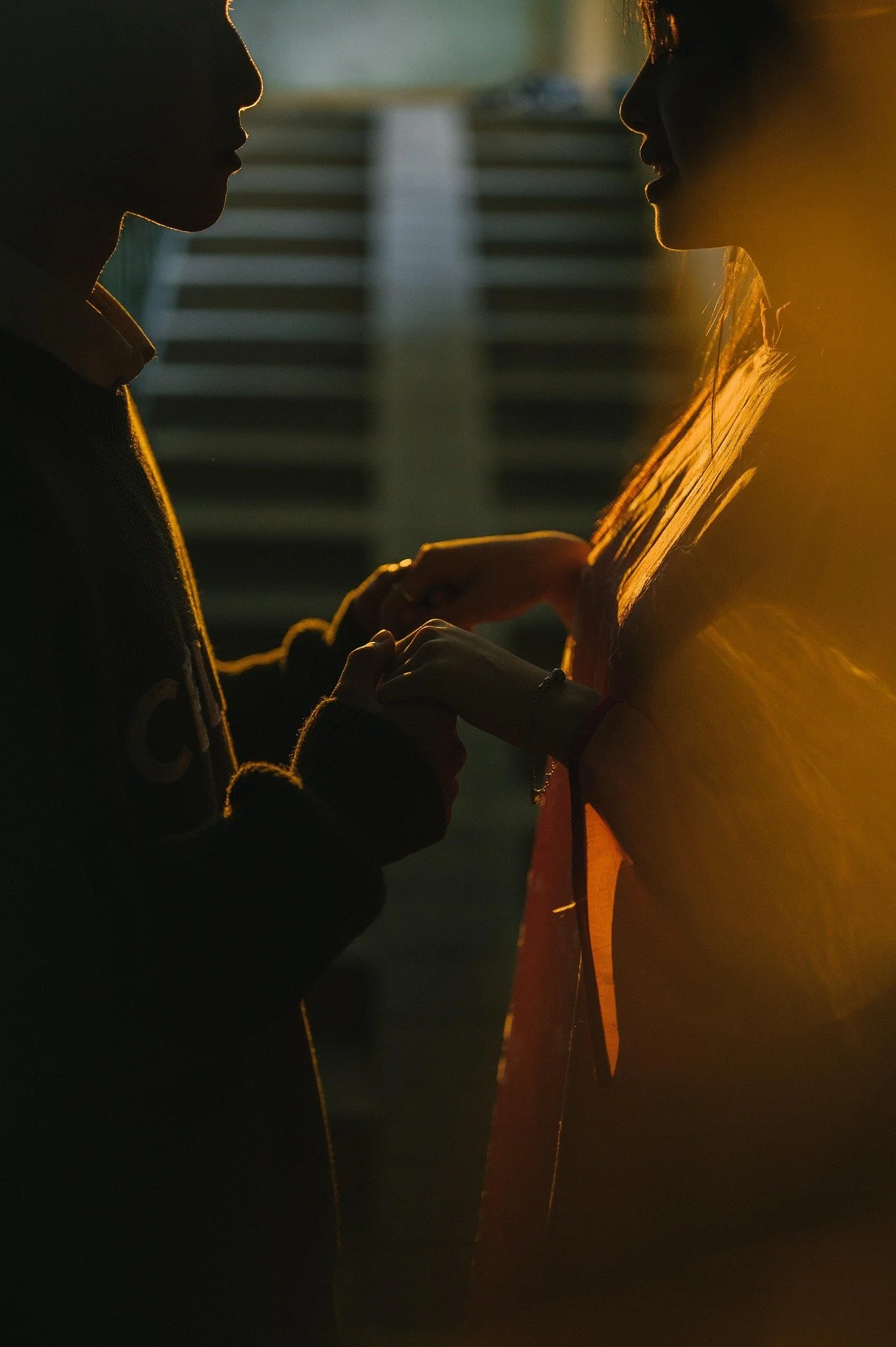 Silhouettes of a young man and woman holding hands during sunset.