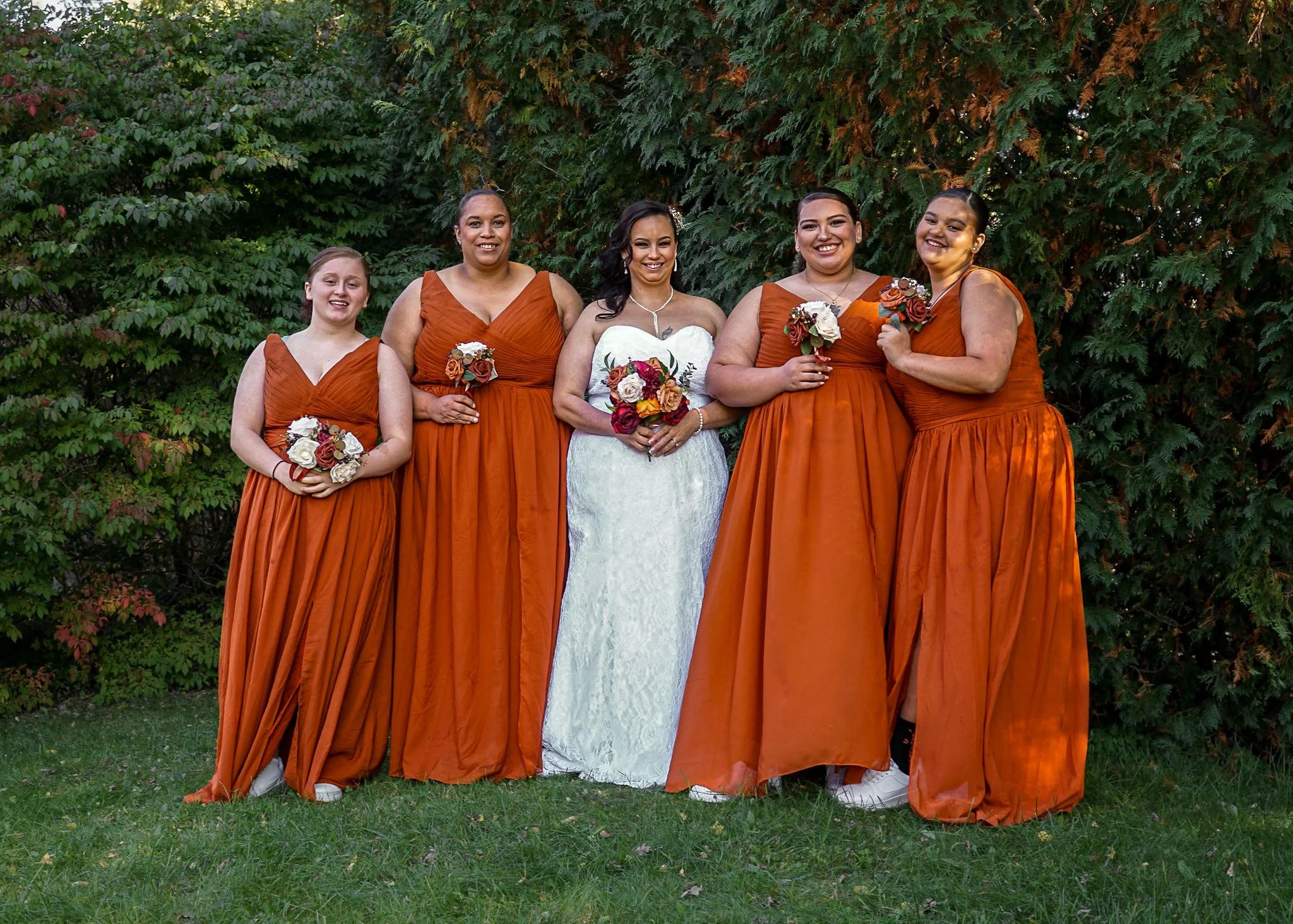 A bride and her bridesmaids are posed together smiling