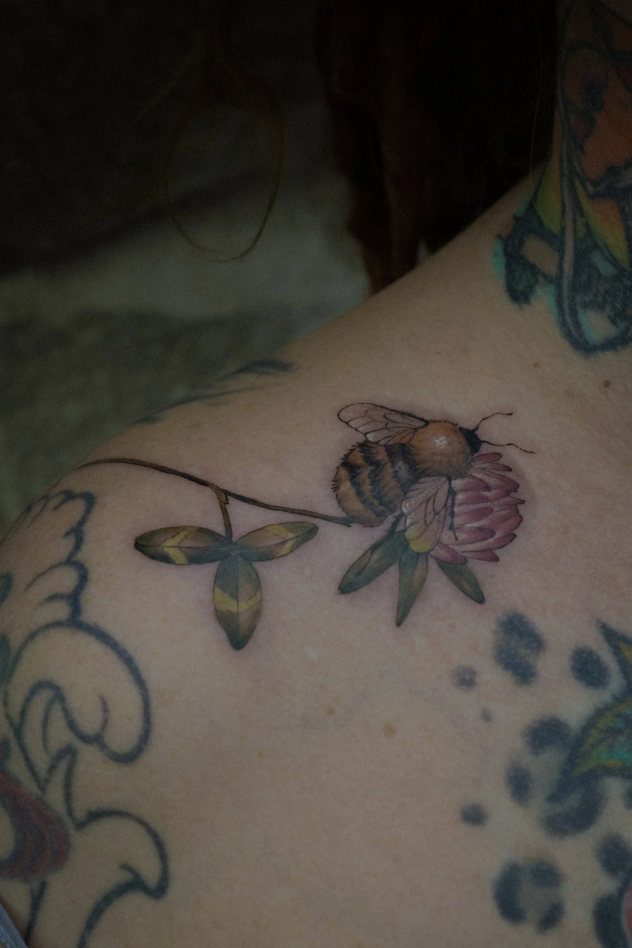 Farbiges Tattoo einer Hummel auf Klee mit Blüte 