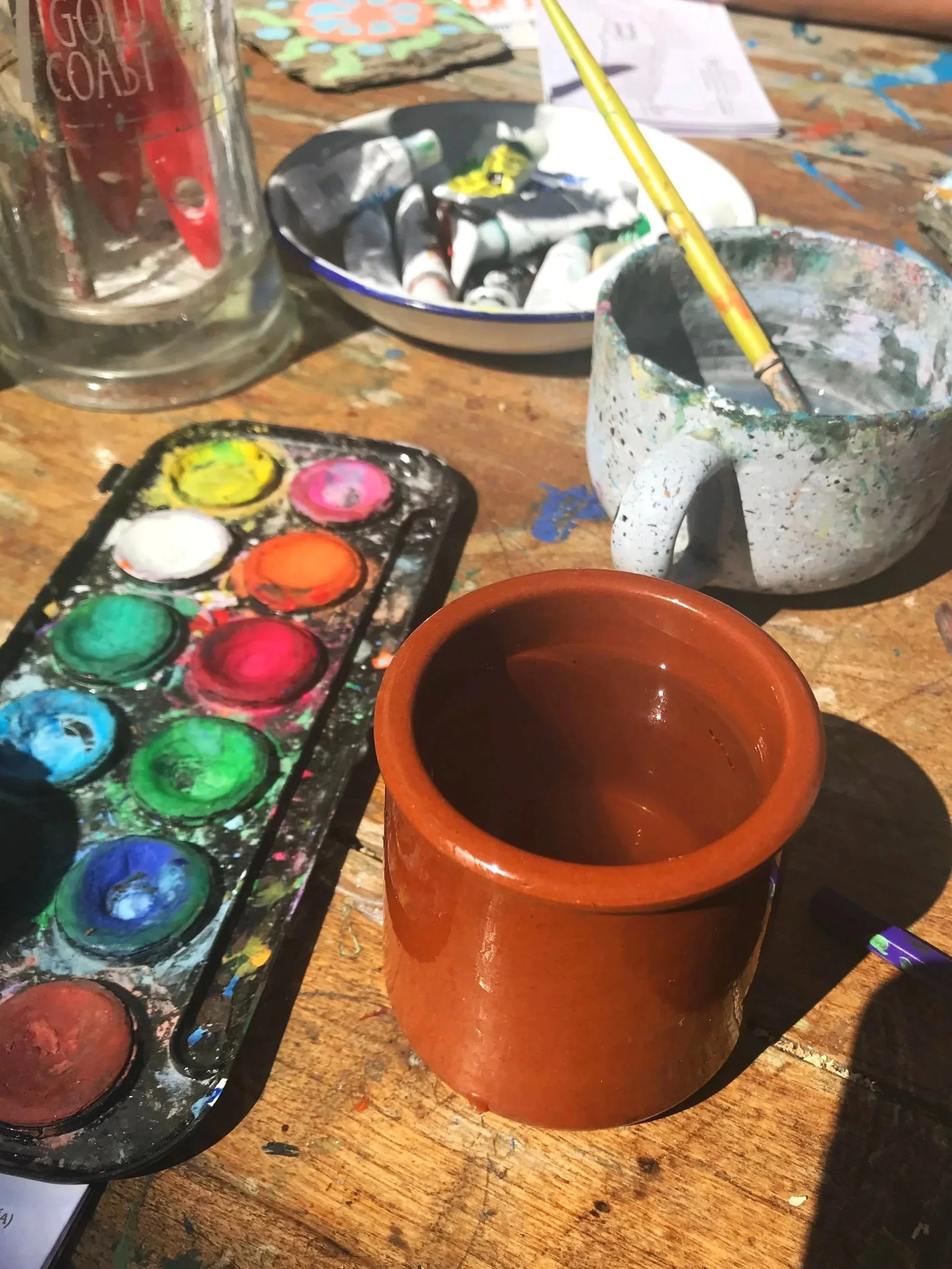 Paint palette and cup of water on a table