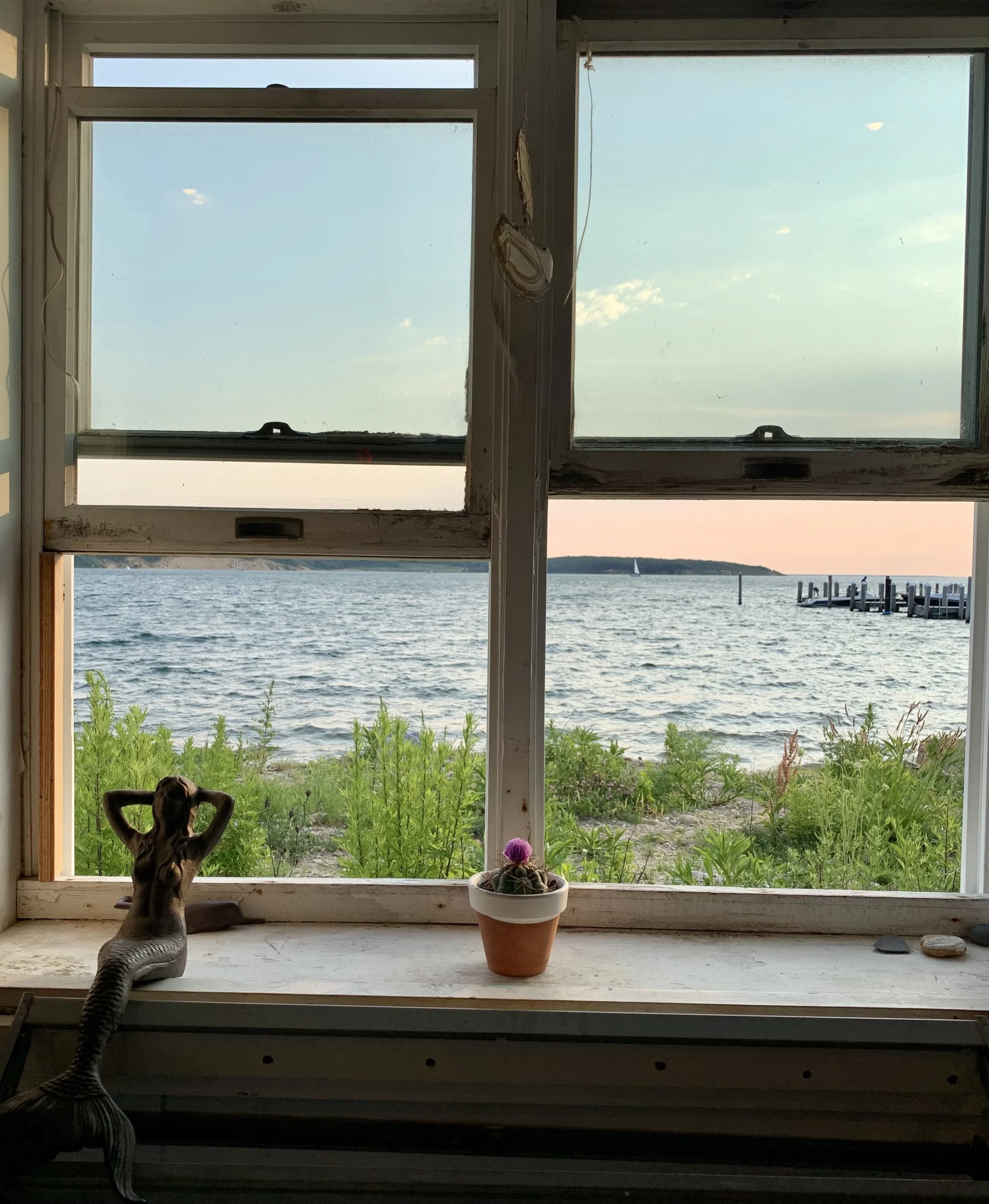 Window overlooking the sea with a small statue on the windowsill