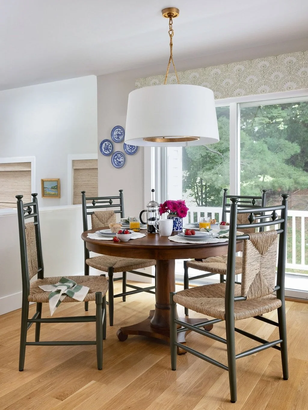 A cozier breakfast nook, without changing the bones of the room.

The marble table felt cool, and the wishbone chairs could not tuck in neatly around it. We brought in a warm wood table and high-back chairs that fit the space more comfortably. A larg