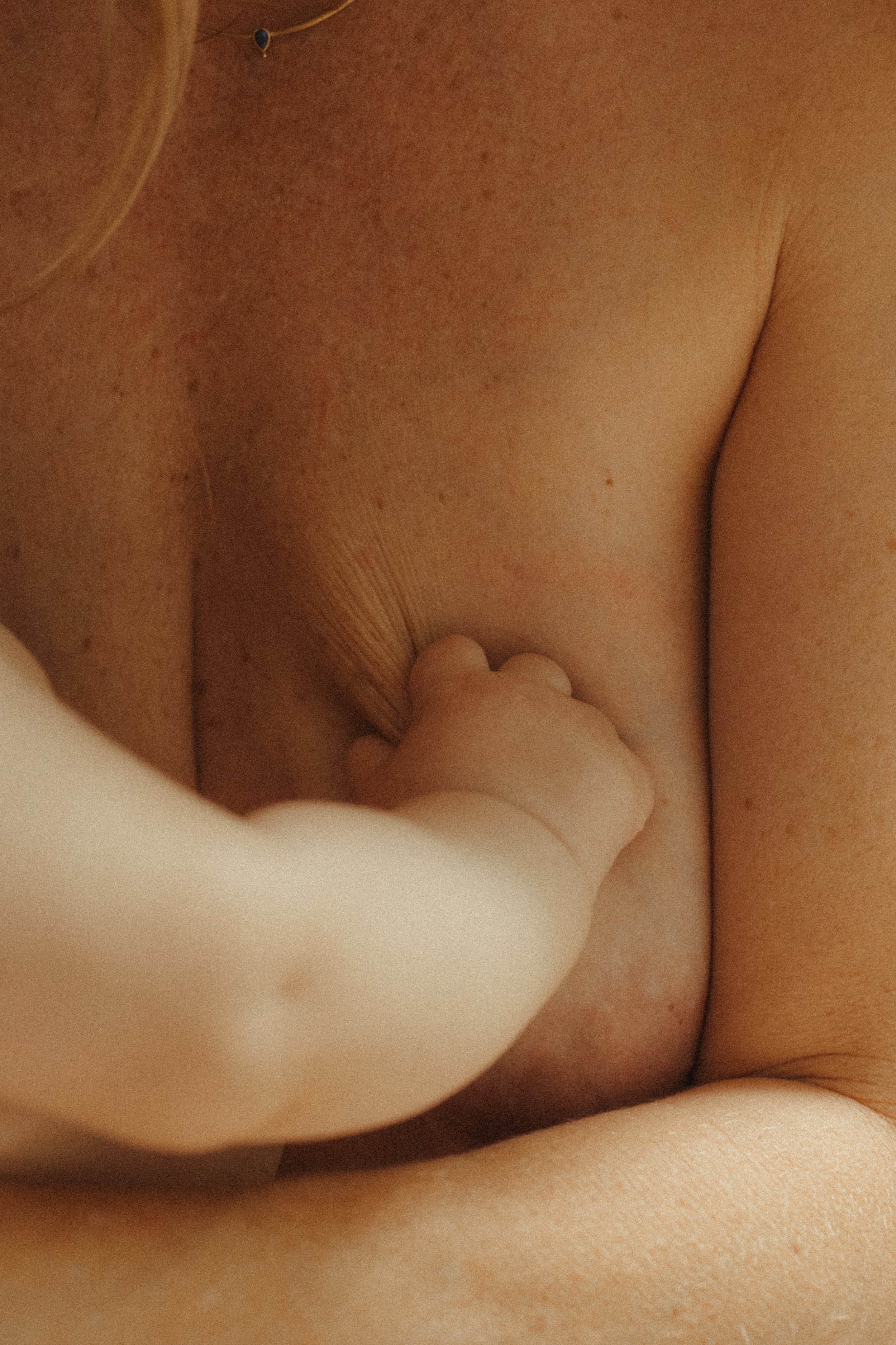 Close-up of a person's chest and arm as a small hand touches their skin.