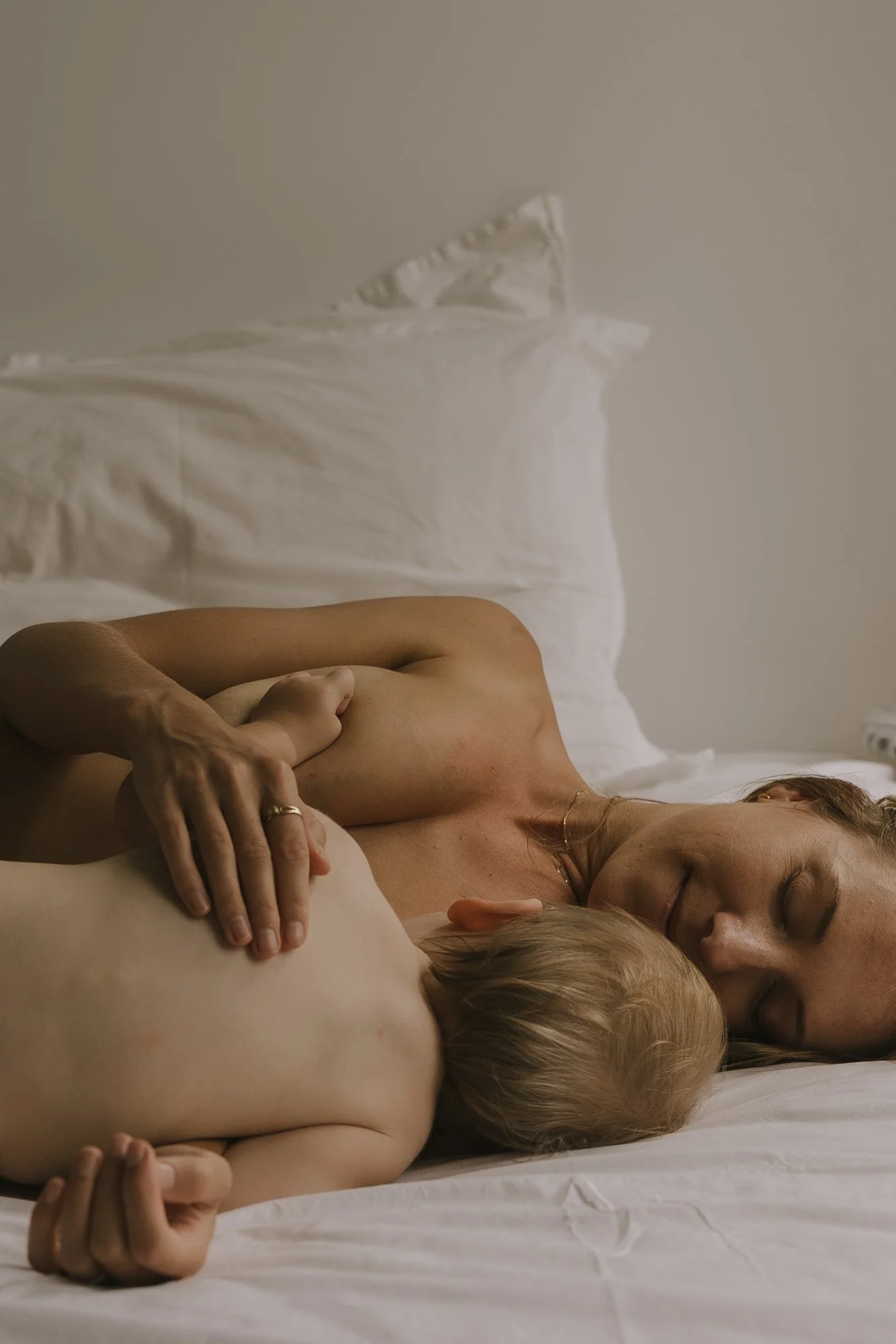 A woman and a child lying on a bed together, embracing each other and sleeping.