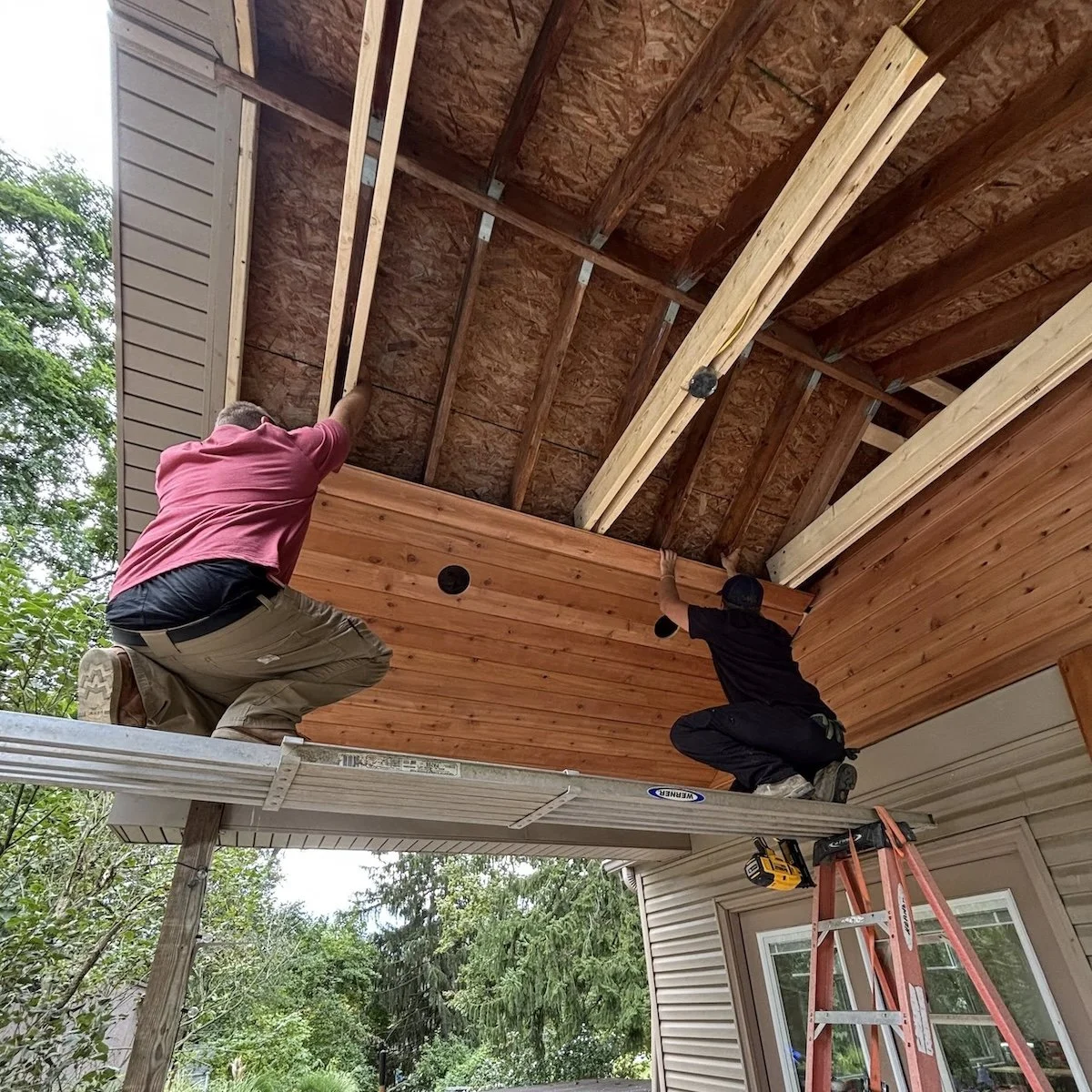 Image of two workmen fitting cedar roof planks