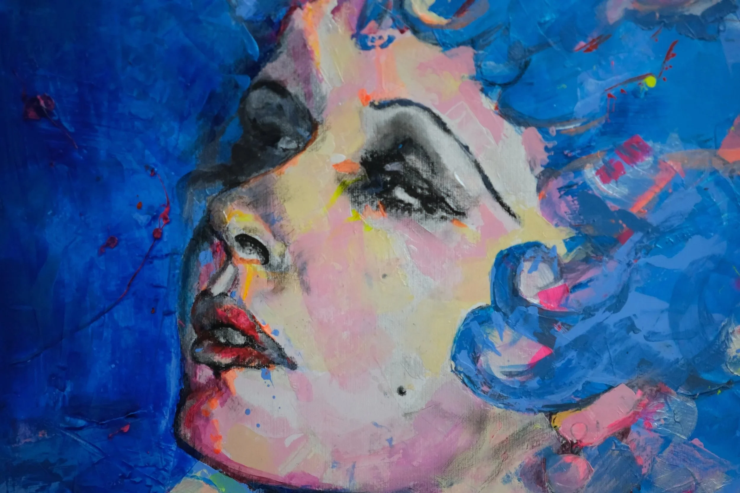 A colorful abstract painting of a woman with closed eyes and red lips, surrounded by blue, pink, and yellow hues.