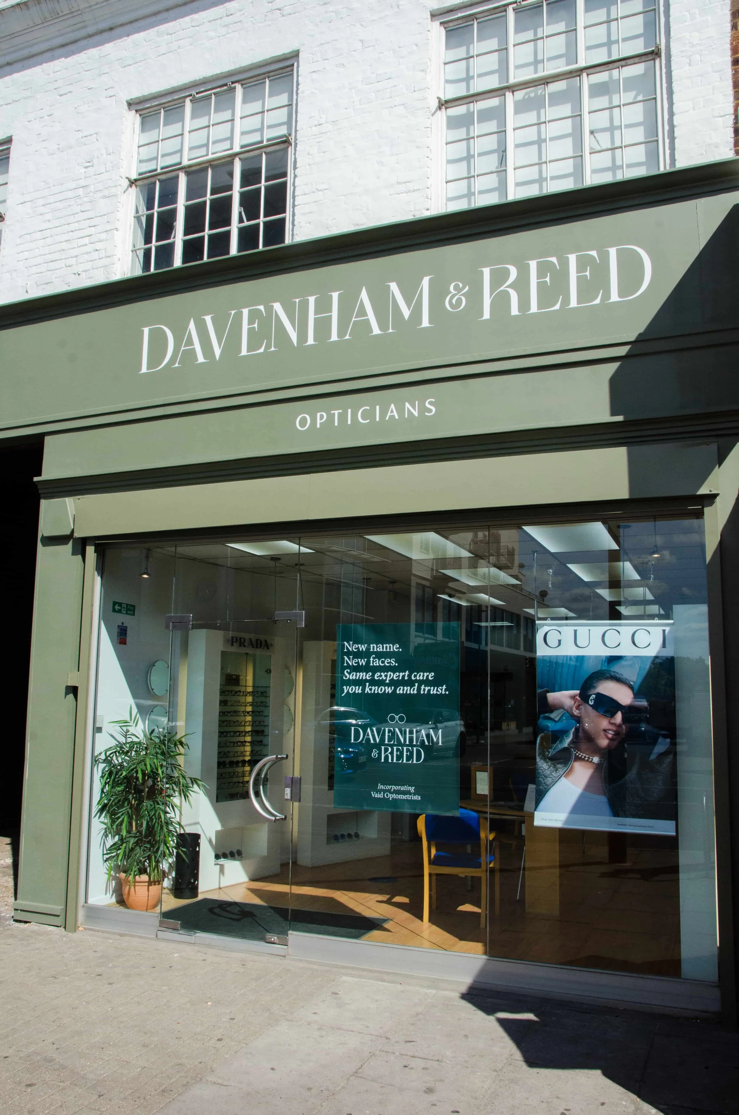 storefront for Davenham & Reed opticians with a promotional sign inside and a large poster of a woman wearing sunglasses.