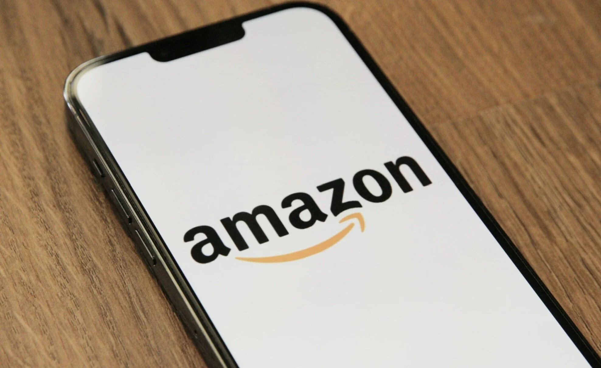 Smartphone displaying the Amazon logo on a wooden surface.