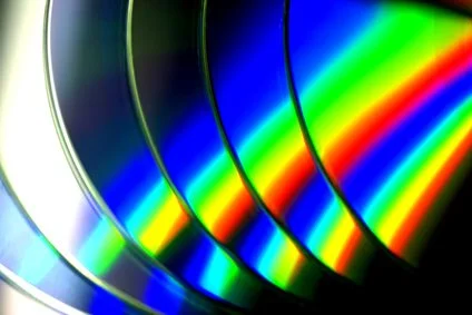 Close-up of multiple rainbow-colored film discs, showing a spectrum of colors with a reflective surface.