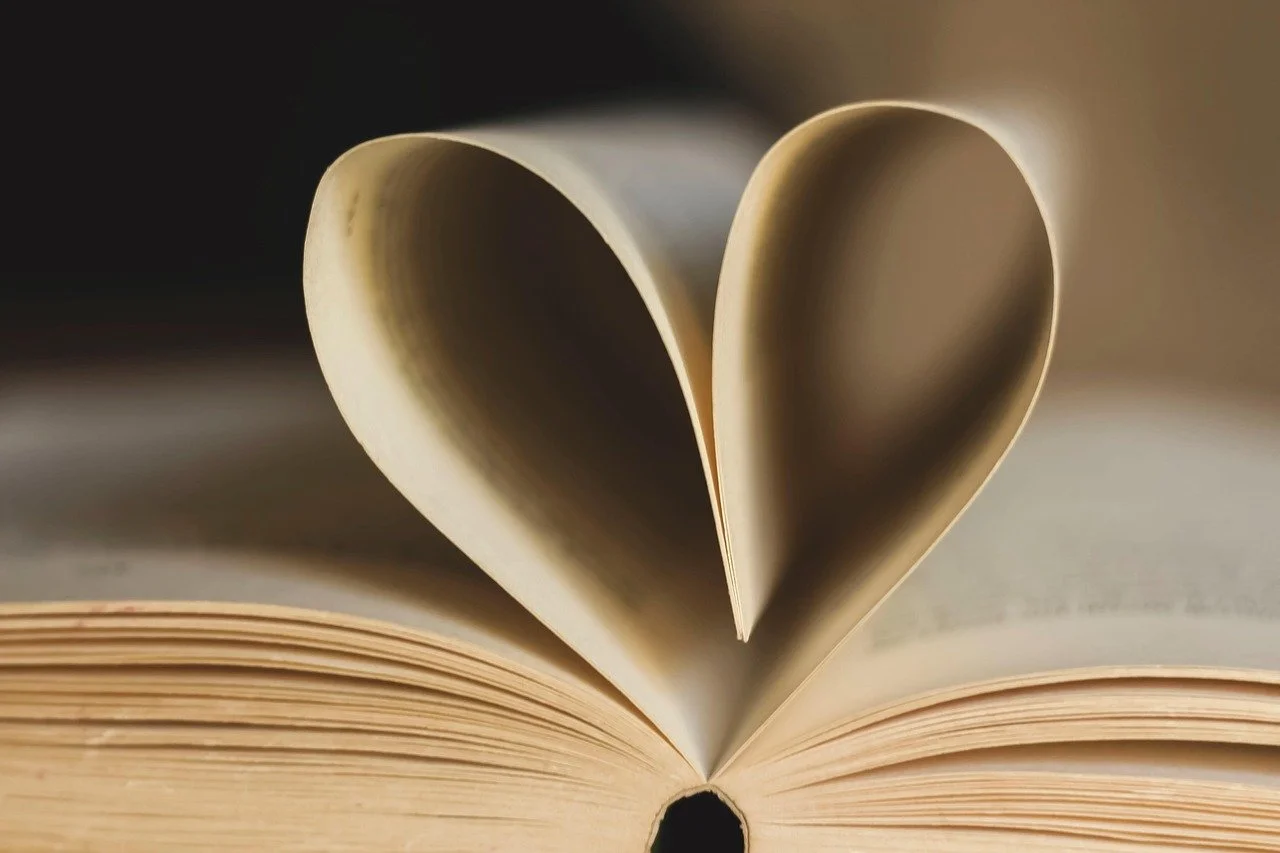 An open book with pages folded into the shape of a heart.