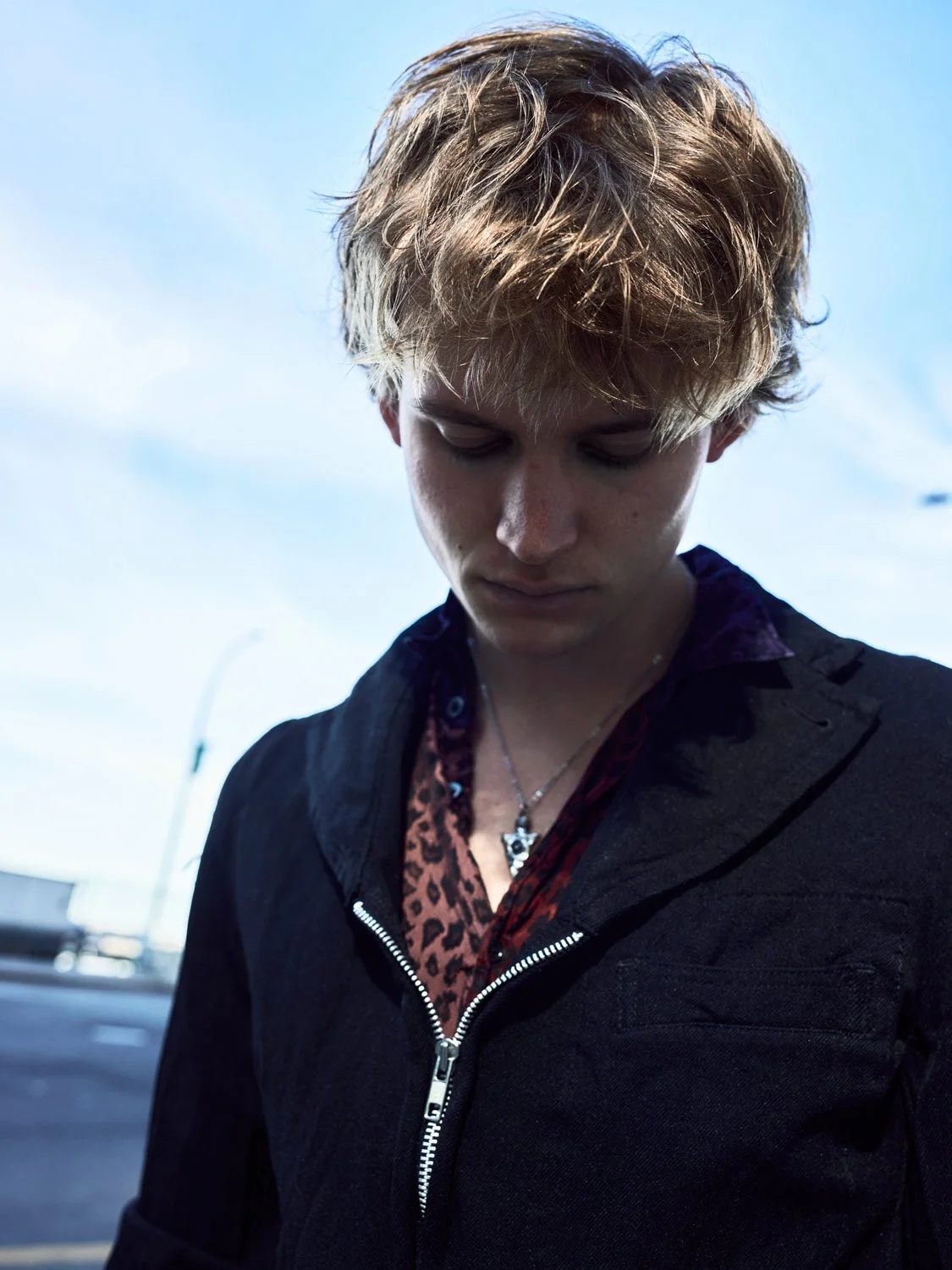 Beauty shot of a male model looking pensive against a pale blu sky.