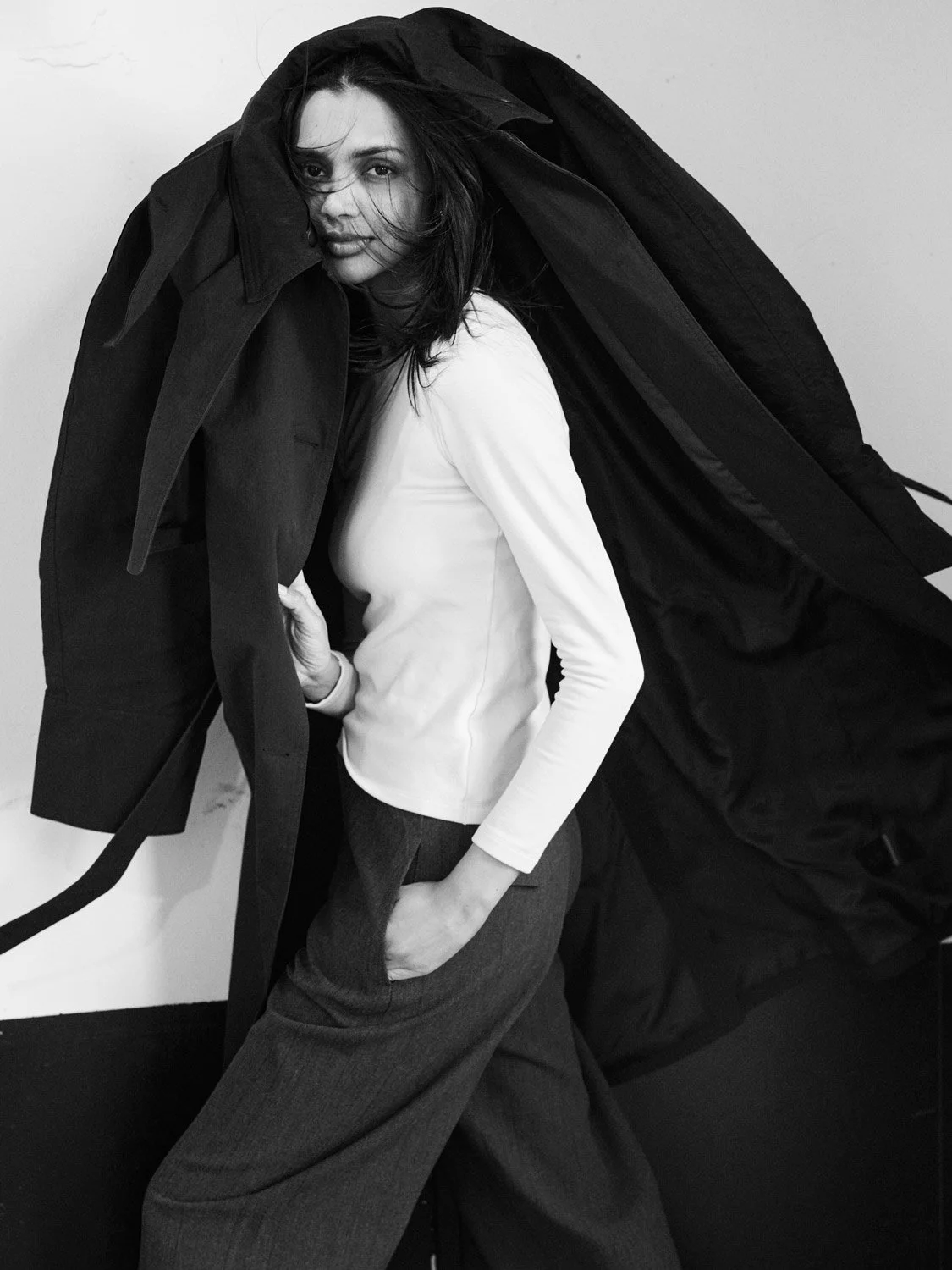 An Indian female fashion model wearing a black coat over her head.