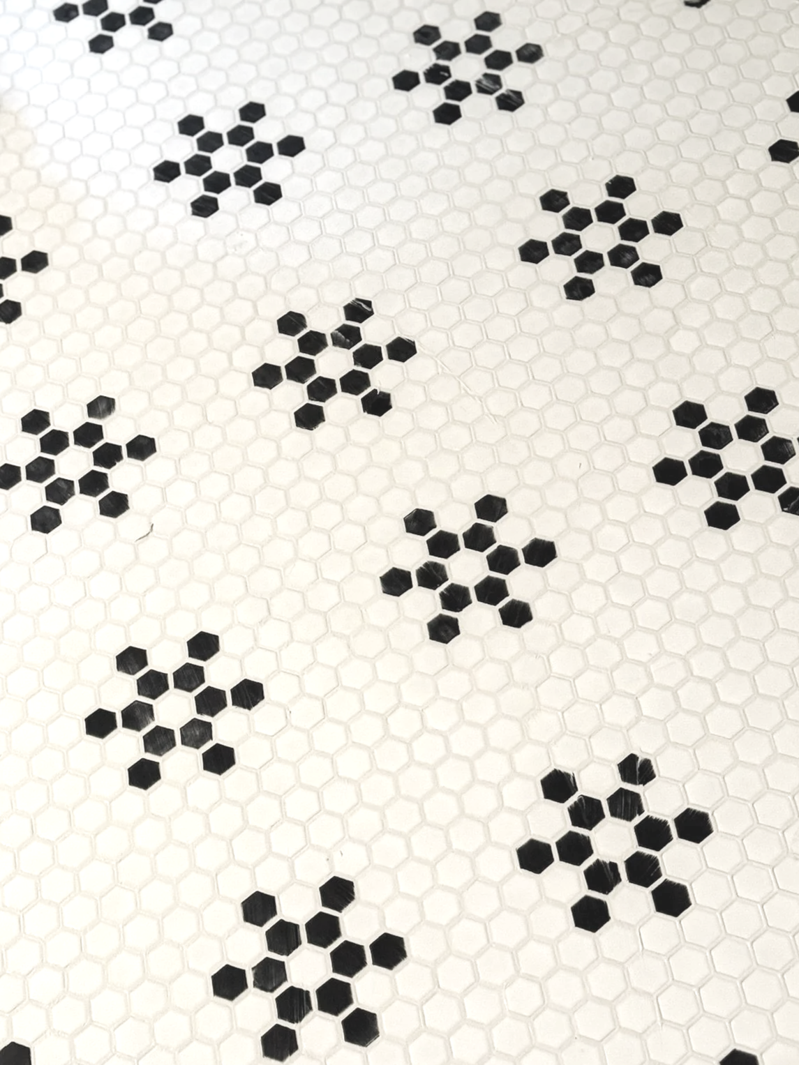 Pattern of white hexagonal tiles with black hexagon clusters arranged in a grid.