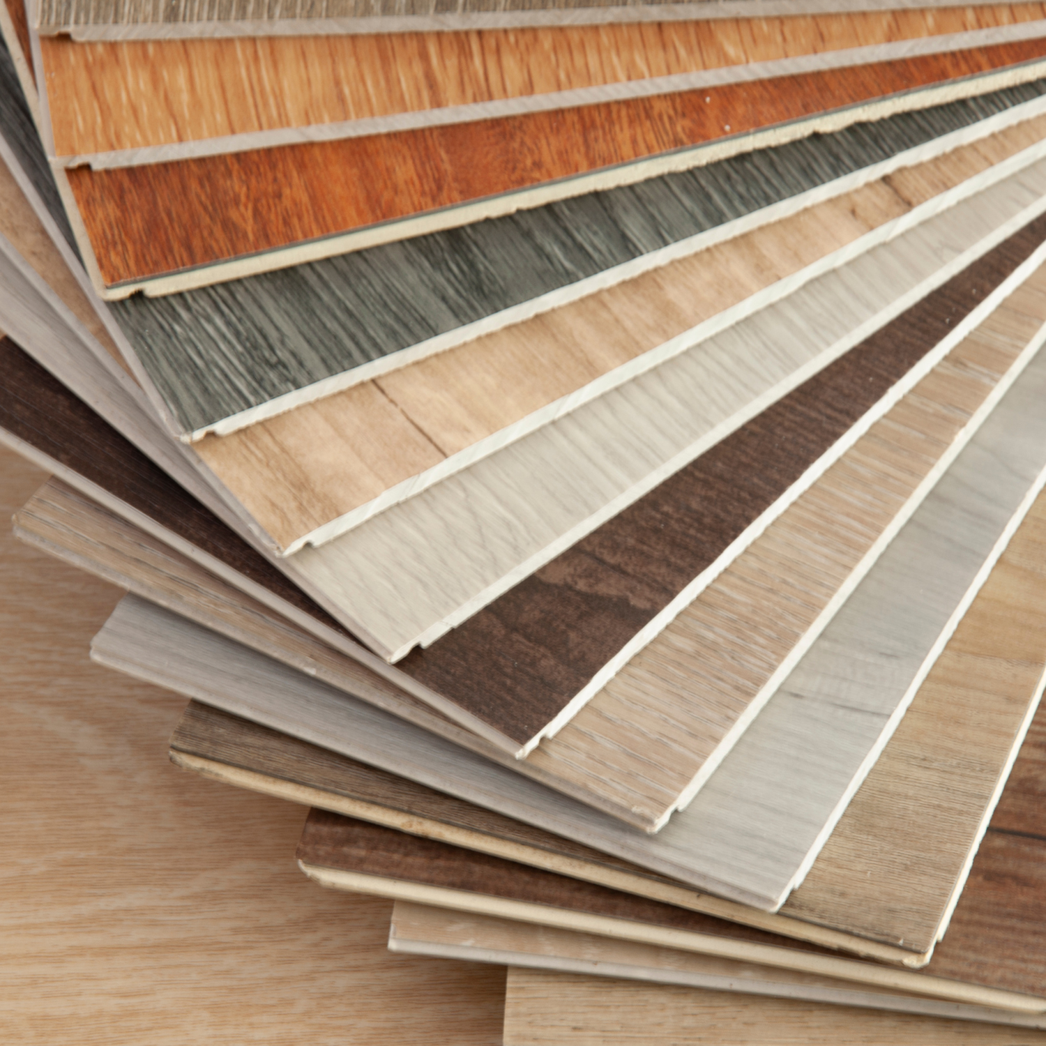 A fan deck of wood laminate flooring samples in various shades and wood grain patterns.