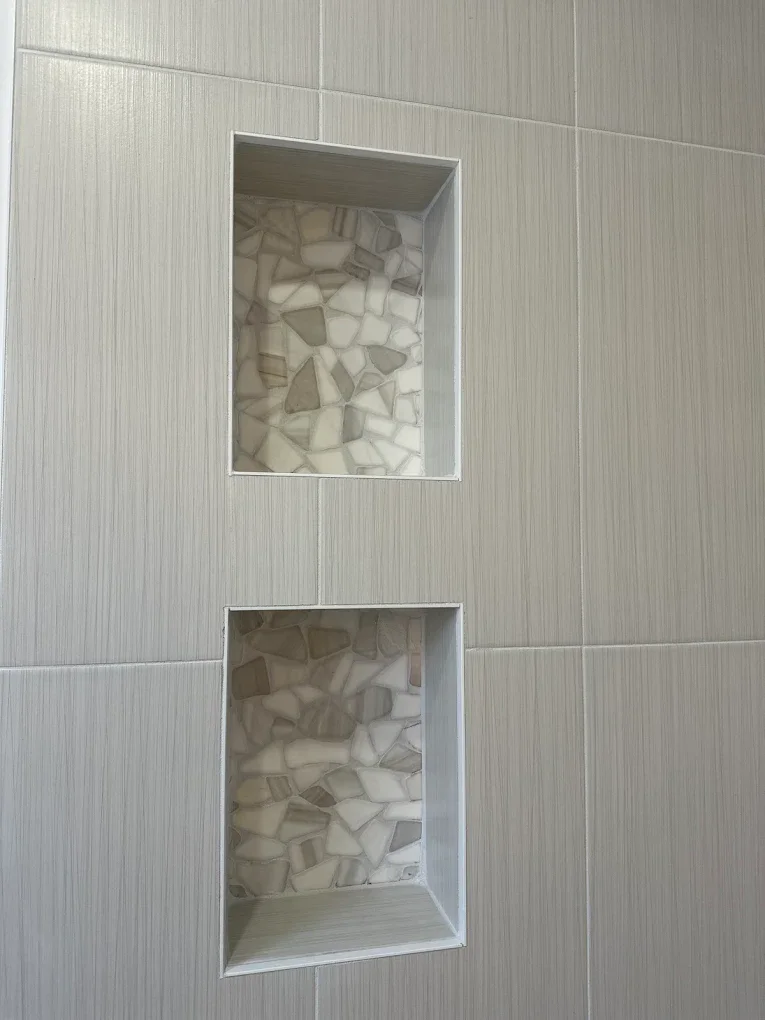 Two rectangular wall niches with decorative stone backs, built into a tiled wall.