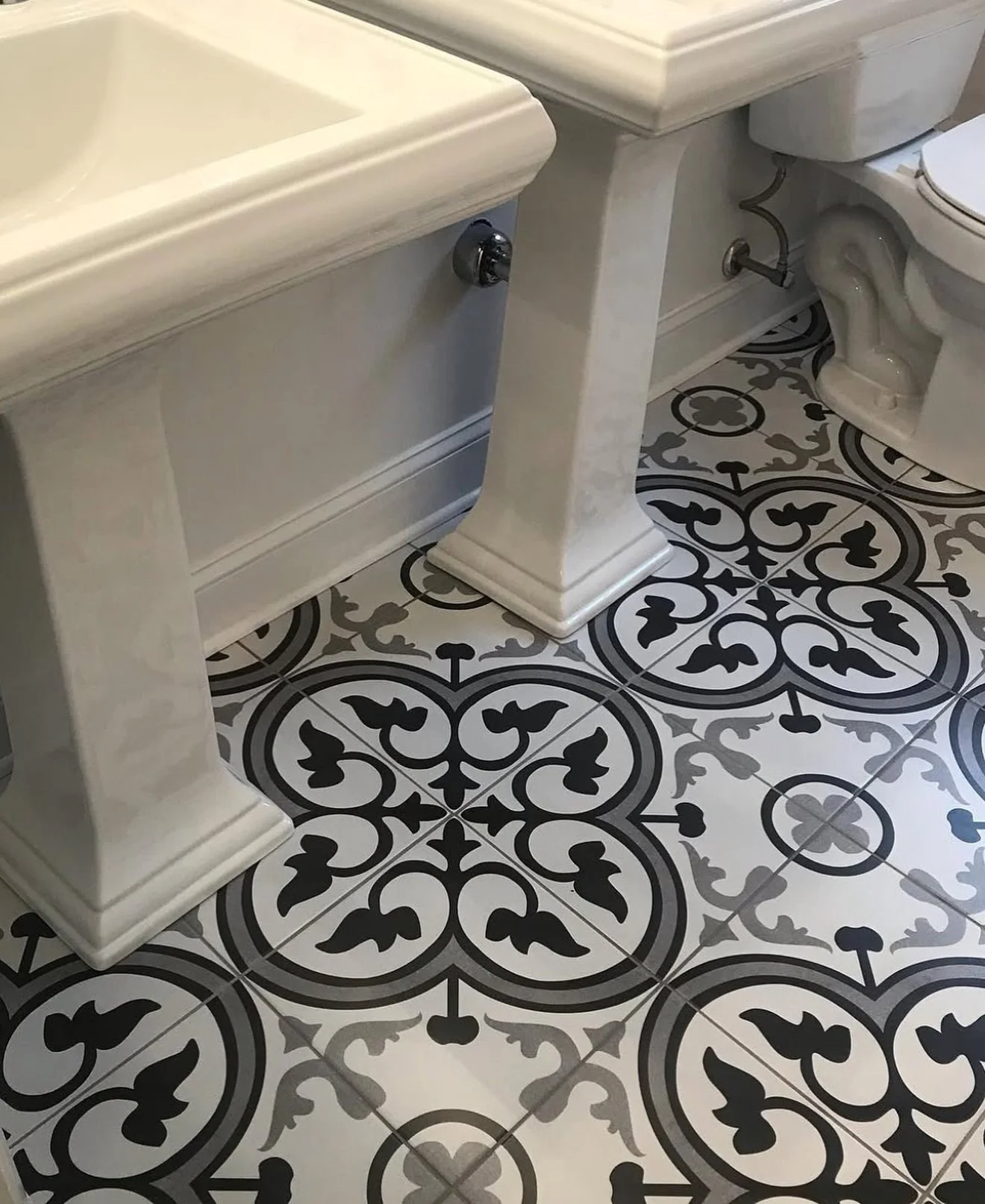Bathroom with patterned black and white floor tiles, white marble sink, and toilet.