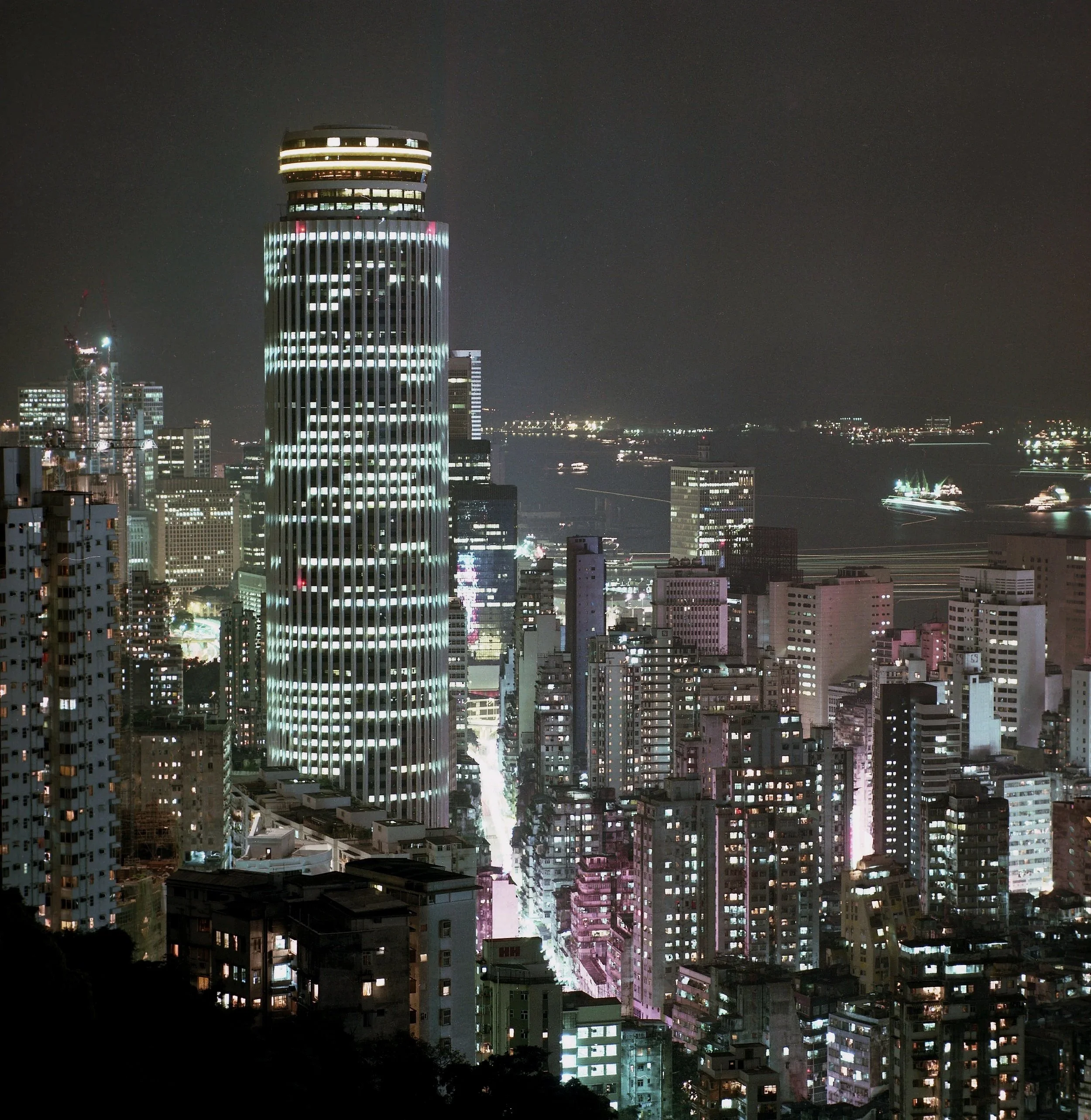 Nighttime cityscape with illuminated high-rise buildings and a dark sky.