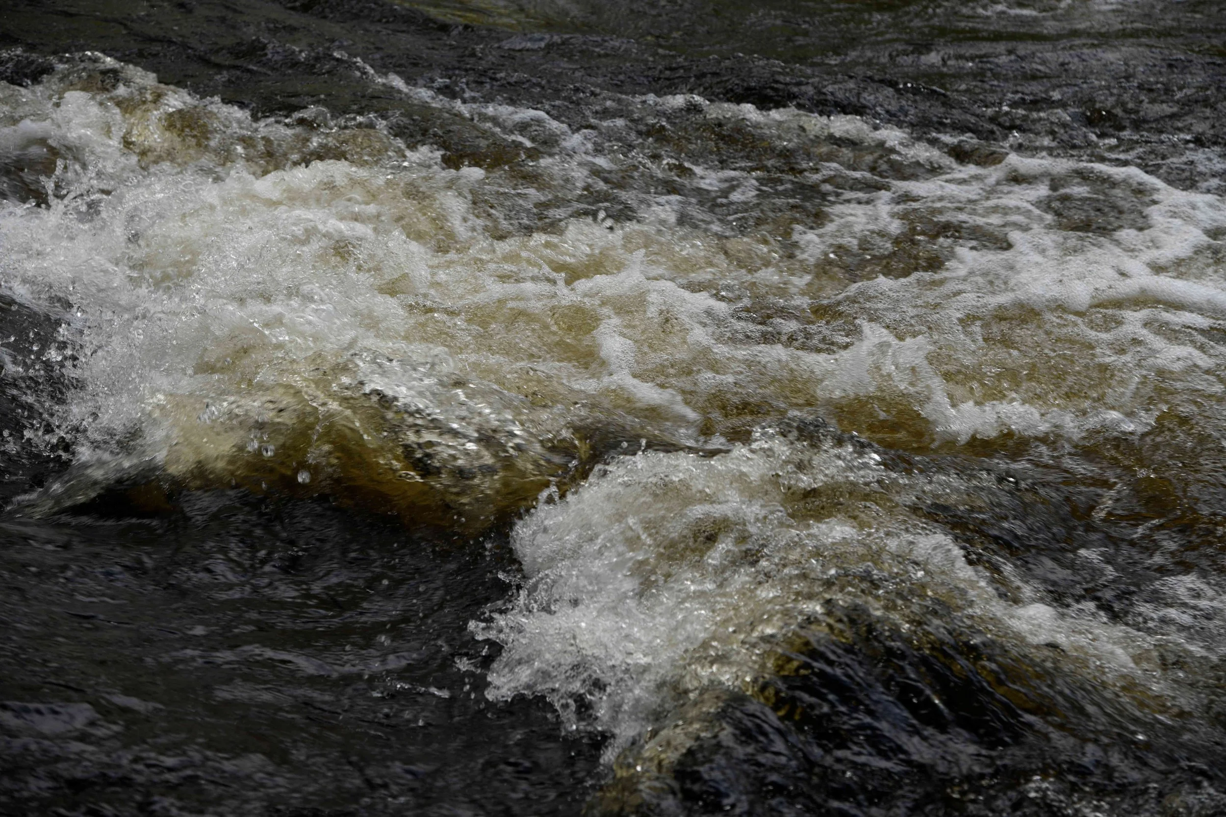 Raging river water flowing rapidly over rocks.