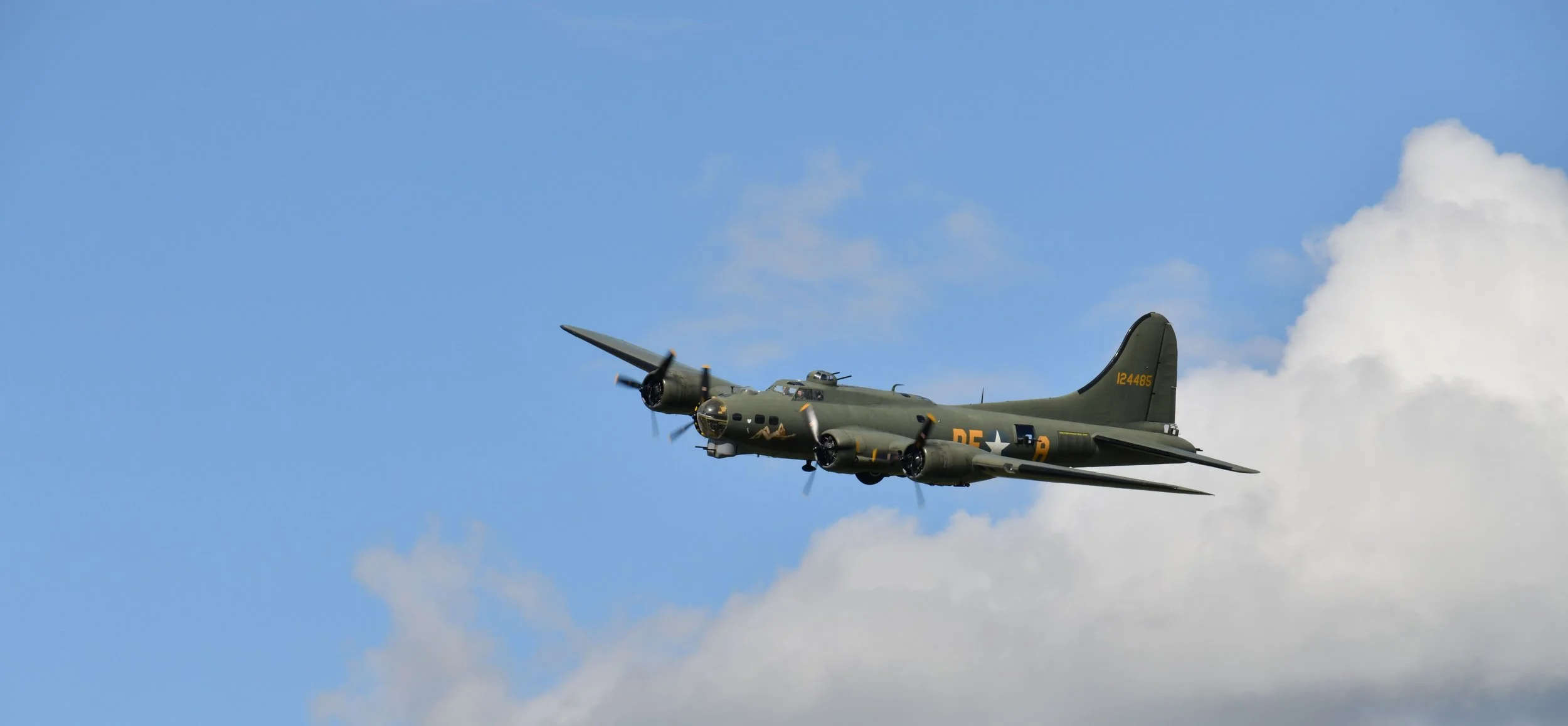 A vintage military aircraft flying in a partly cloudy sky.