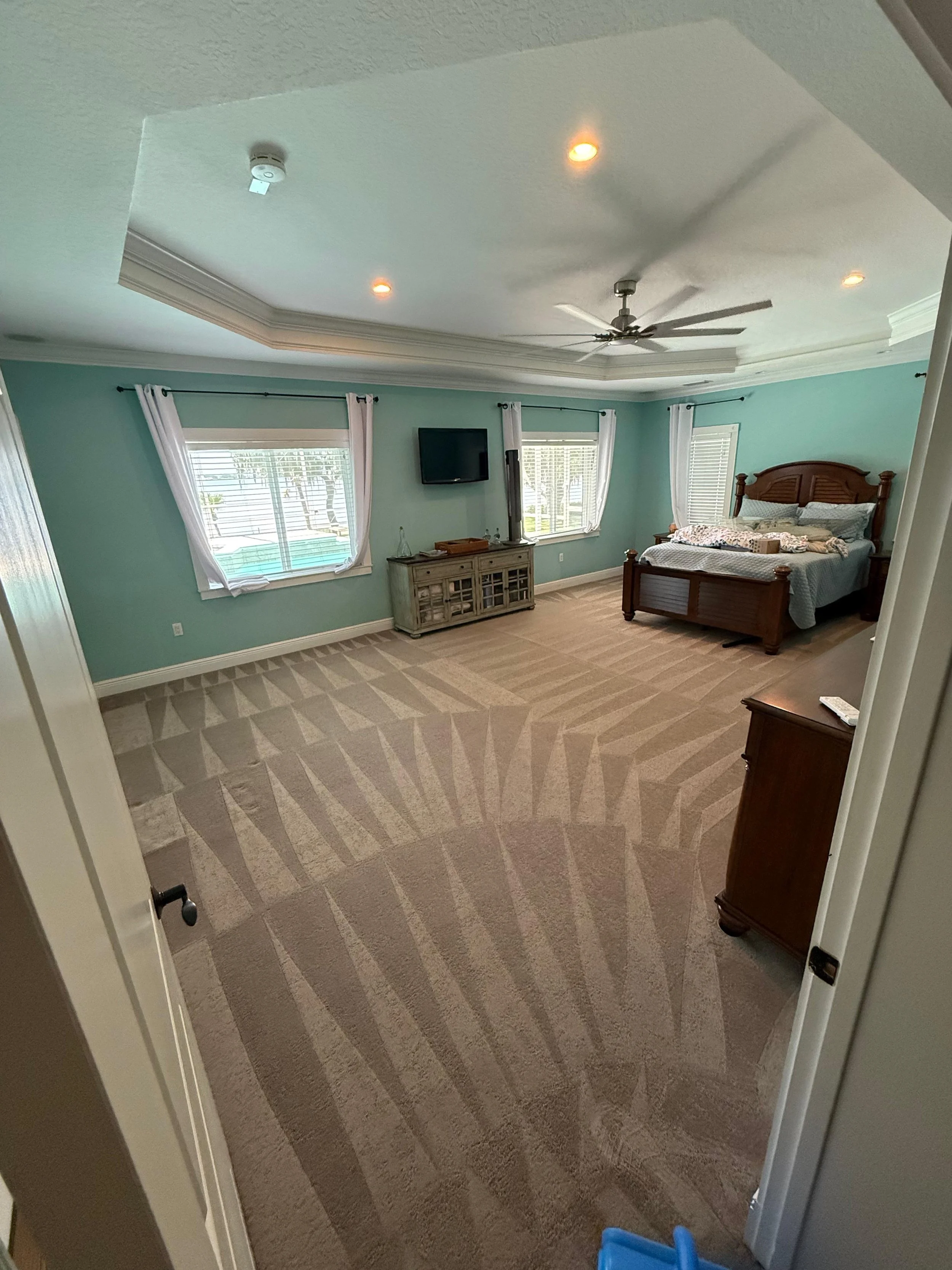 Technician using carpet wand in living room; soil lines lifted and texture restored during professional carpet cleaning in Orlando.