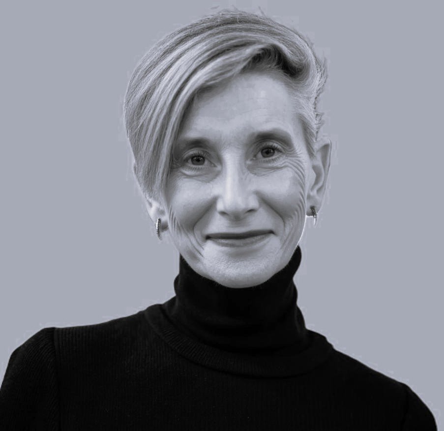 Black and white portrait of a woman smiling, with short hair and wearing a collared shirt.