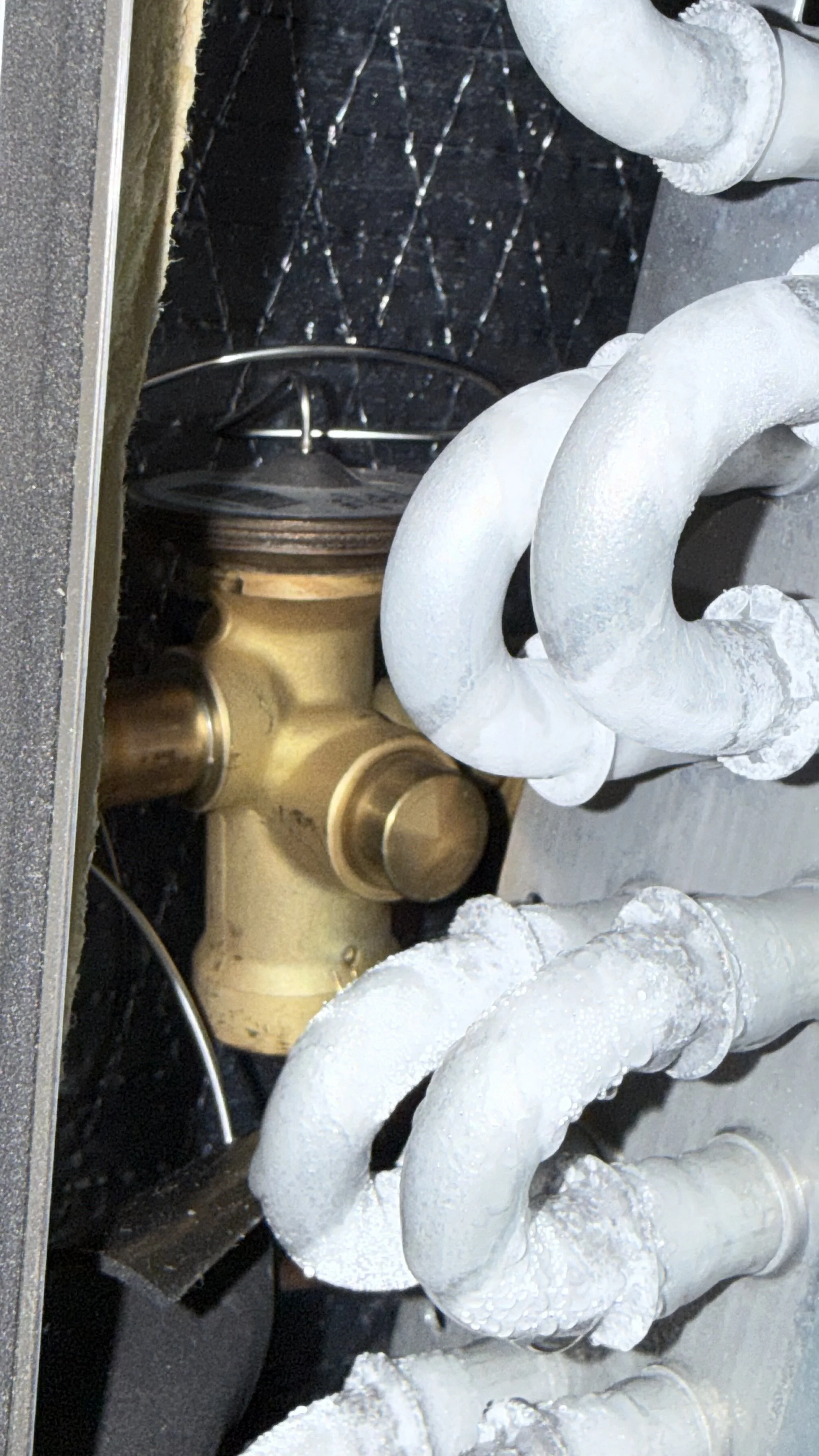 Close-up of a kitchen or bathroom sink faucet assembly with wrapped pipes for insulation.