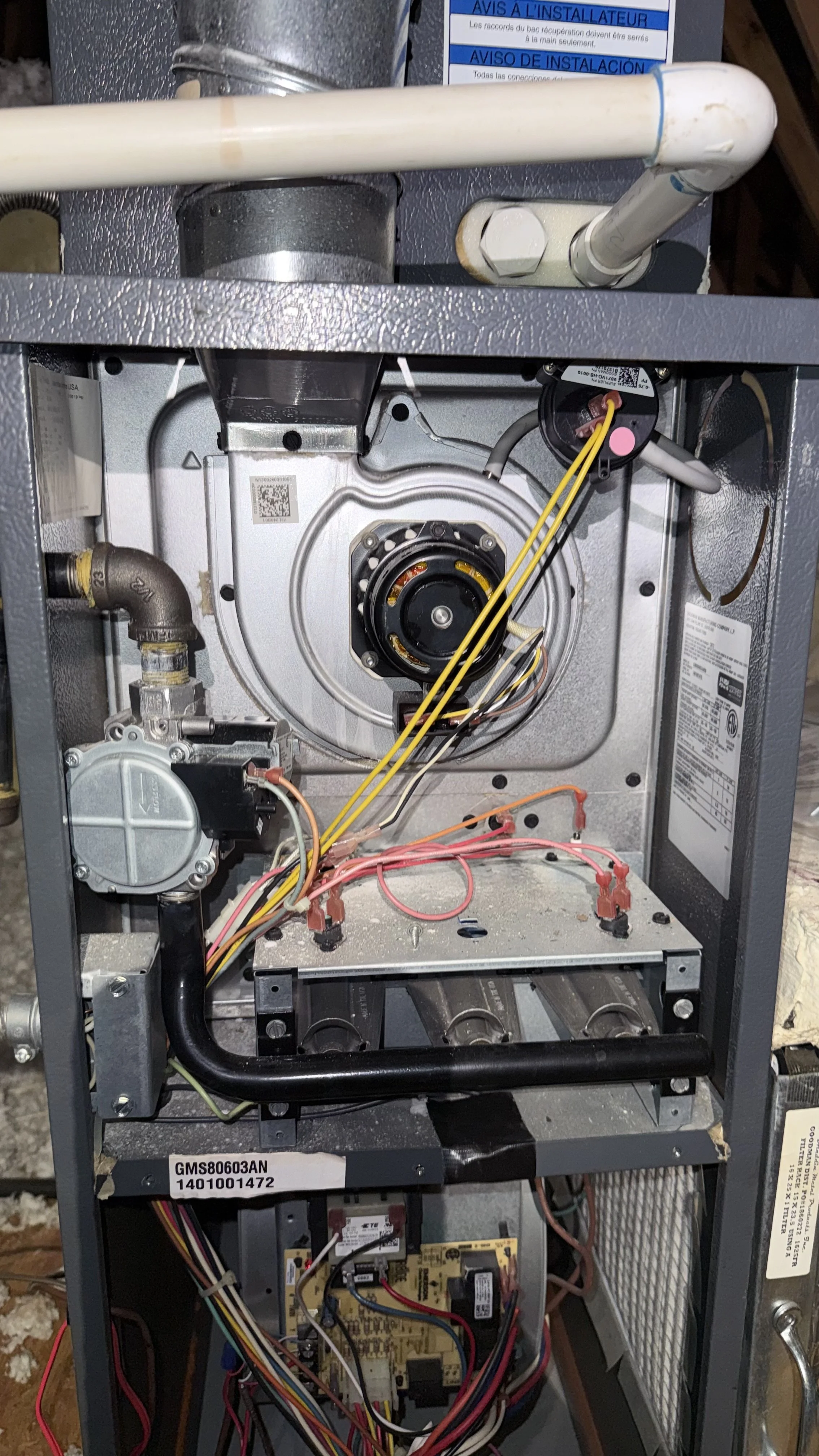 Interior view of an opened furnace or HVAC system showing various mechanical and electrical components, including wiring, pipes, and motors.