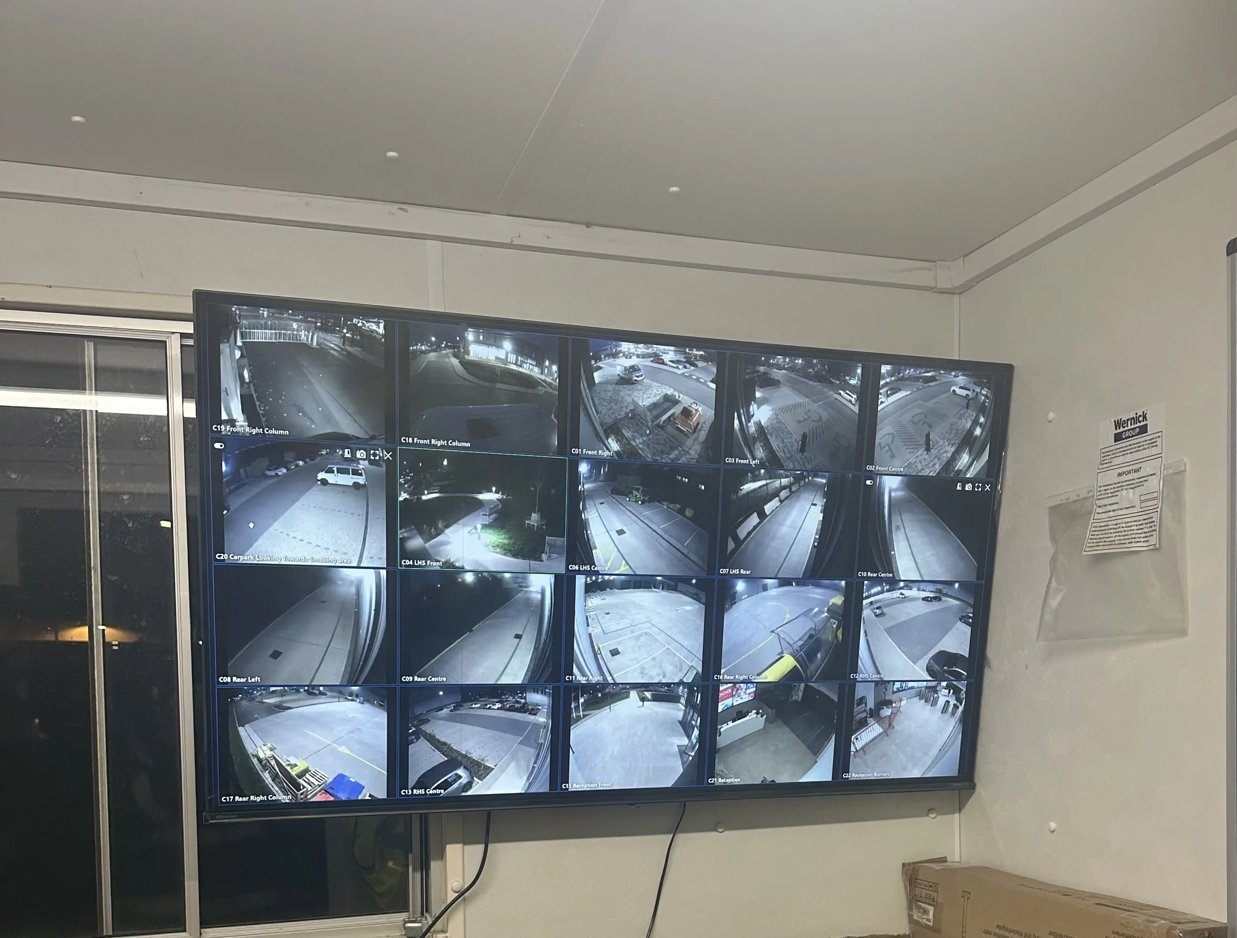 A person sitting at a control station with multiple monitors displaying various surveillance footage, maps, and data charts.