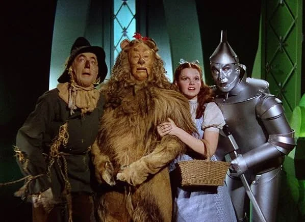 The image shows characters from the Wizard of Oz, including the Cowardly Lion, Tin Man, Dorothy, and Scarecrow, standing together in what appears to be a menacing castle interior.