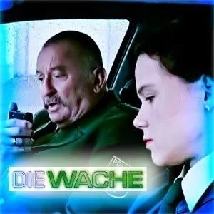 Two men sitting inside a vehicle, one using a phone and the other looking down, with a police logo for 'Die Wache' in the image.