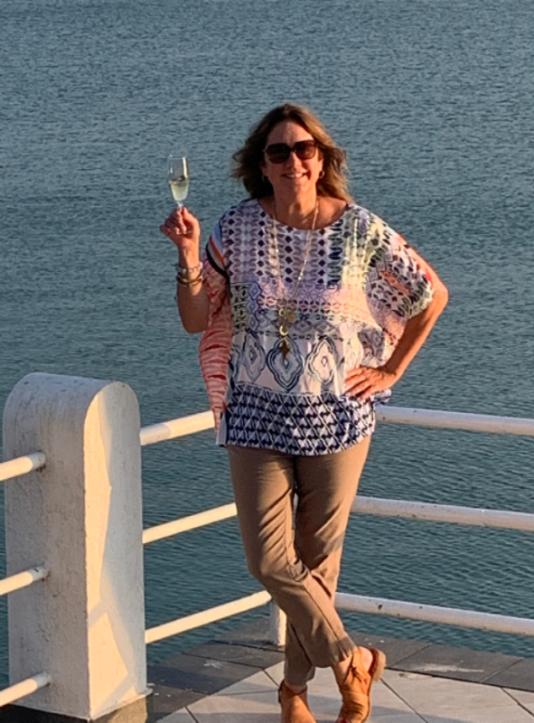 Woman in sunglasses holding a glass of champagne on a pier over water