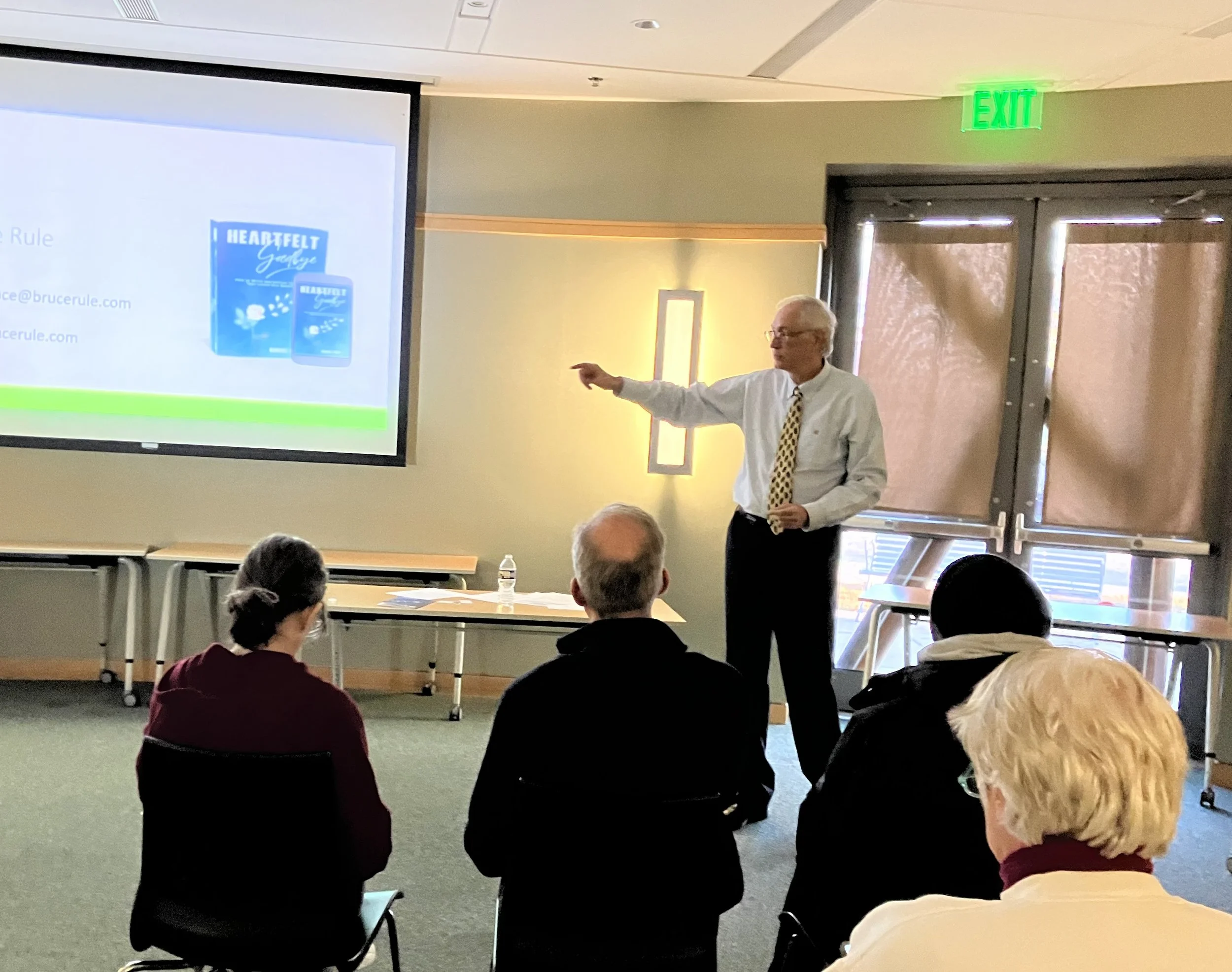 Bruce Rule giving a presentation in a conference room with four attendees sitting and listening.