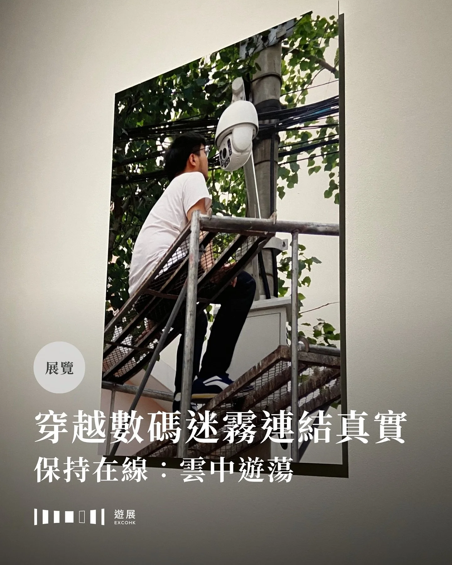 除了早已在網上引起不少迴響，以機械臂清理地上液體的裝置藝術作品《難自禁》外，那個大館展覽還有什麼看頭？

走進藝方展廳，彷彿踏入一個漂浮於雲端的漫遊。螢幕閃爍、訊號斷續、數據流動，展覽《保持在線：雲中遊蕩》不僅是一次視覺與感官的衝擊，更是一場對當代人類處境的深刻提問。觀眾在虛實難分的時代中，可以在作品的引導下思考數碼科技如何滲透、重塑我們的日常，並反思該如何建立真實而有意義的連結。

展場中，一幅照片引來不少觀眾注視：一場靜默的對峙被定格其中。藝術家靜靜地坐在北京街頭的鐵架上，目光直視燈柱上的監