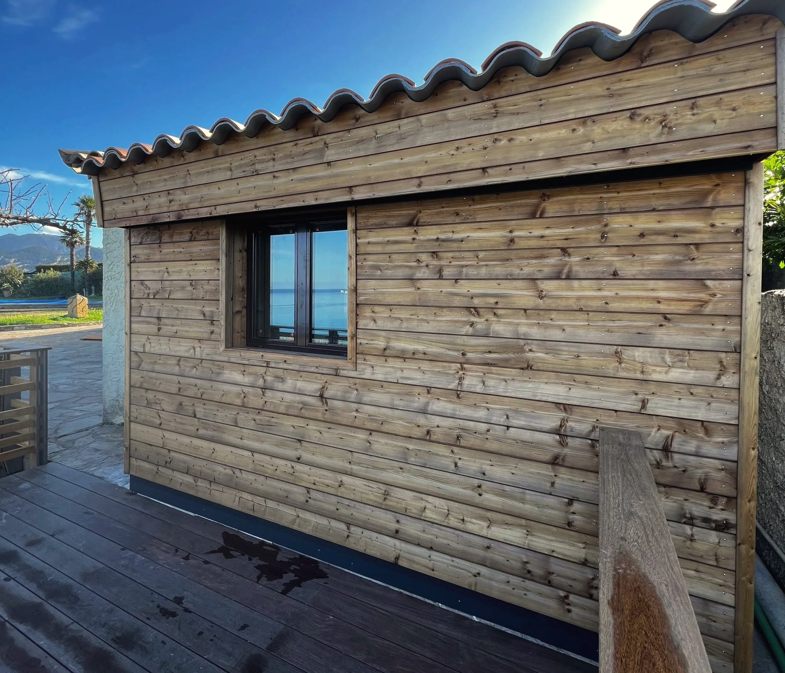 Extension en ossature bois avec une fenêtre noire, située en extérieur