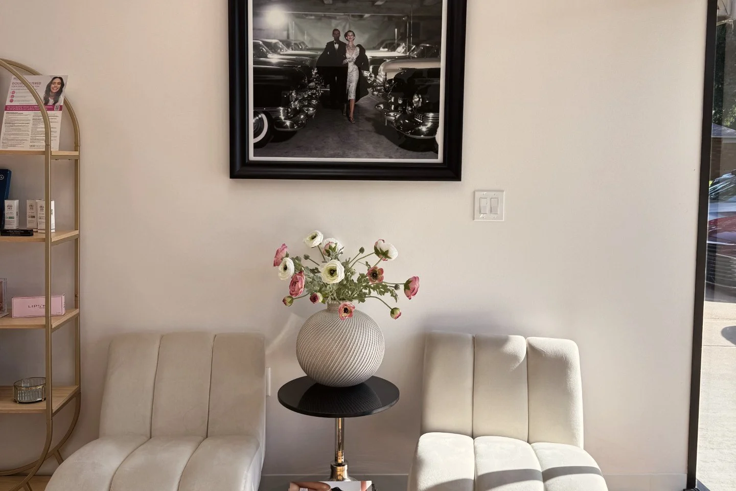 The Reforge Med Spa waiting area, with two cream chairs, fresh flowers on a side table and window light.