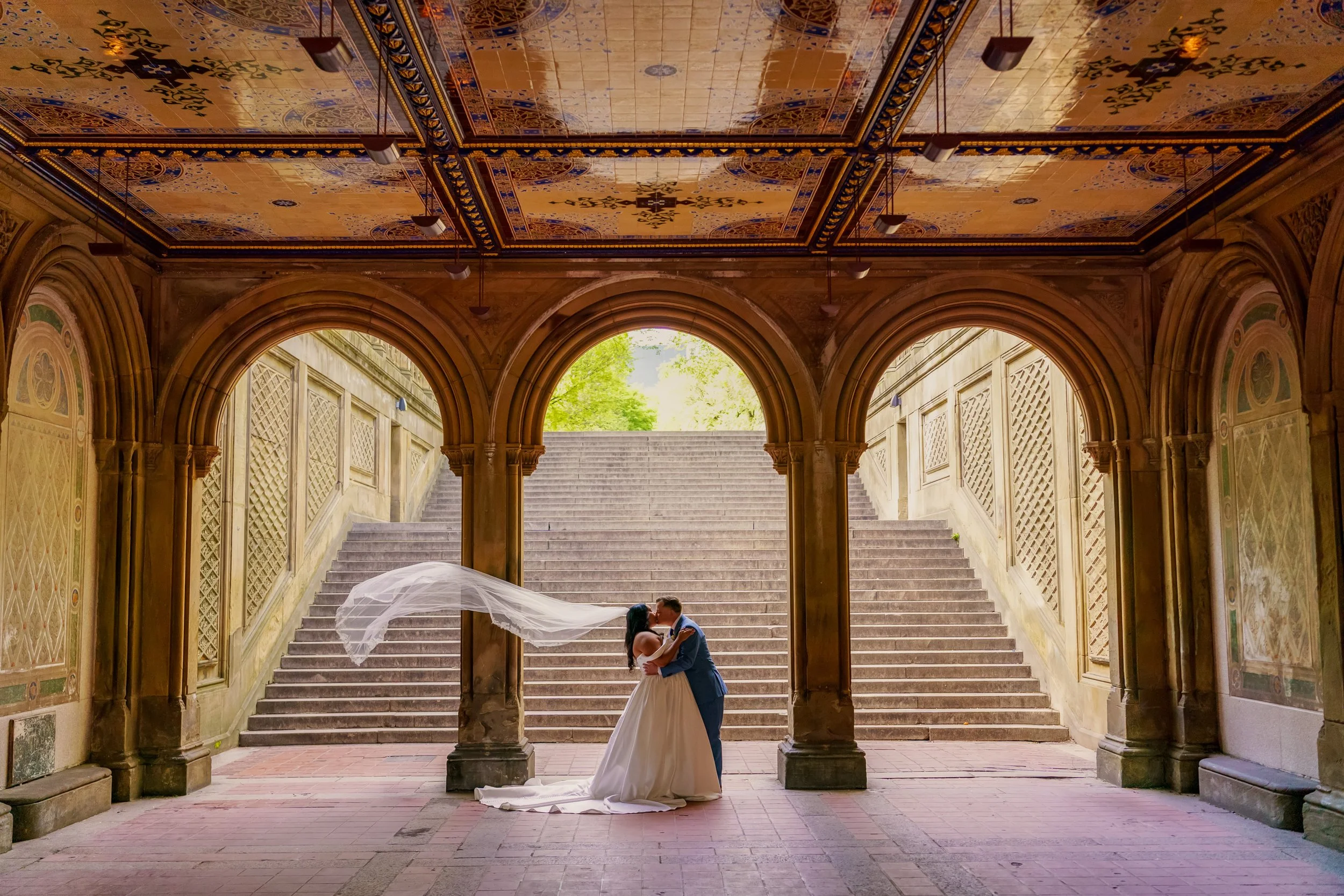 A bride and groom posed under the Bethesda Terrace in Central Park