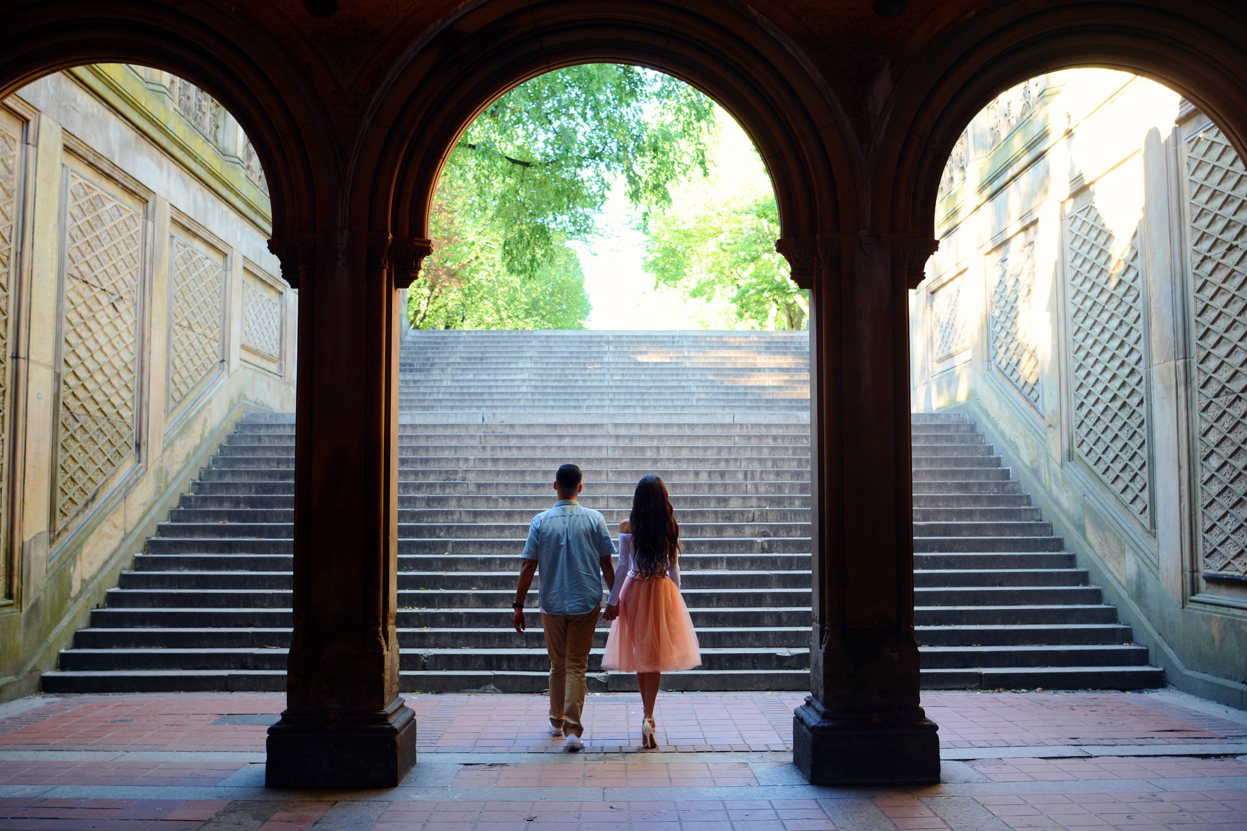 A couple holding hands under the Bethesda Terrace in Central Park