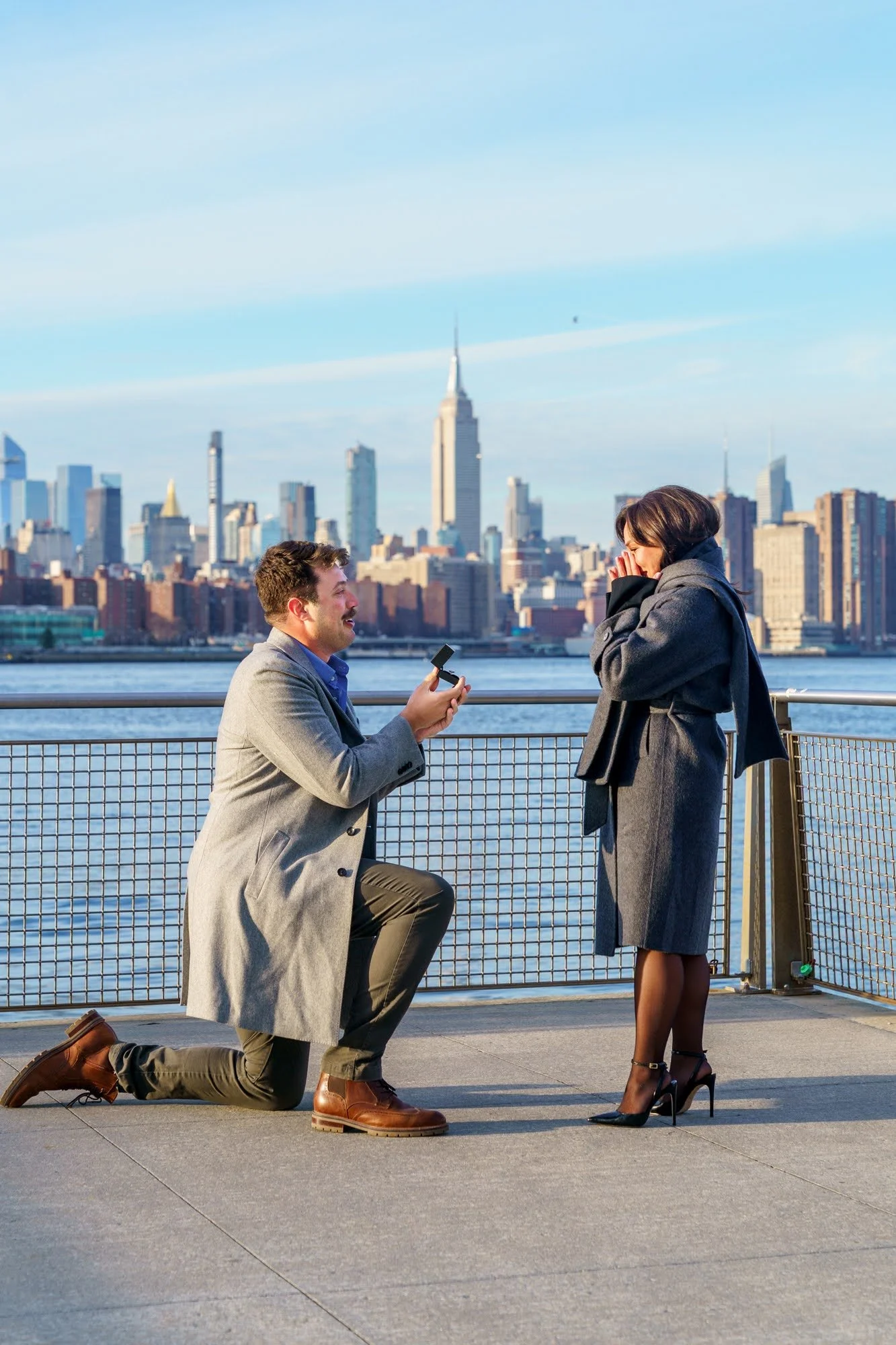 A man on one knee proposing to a woman by the water with the Empire State Building and skyline in the background

Williamsburg Brooklyn proposal photographer