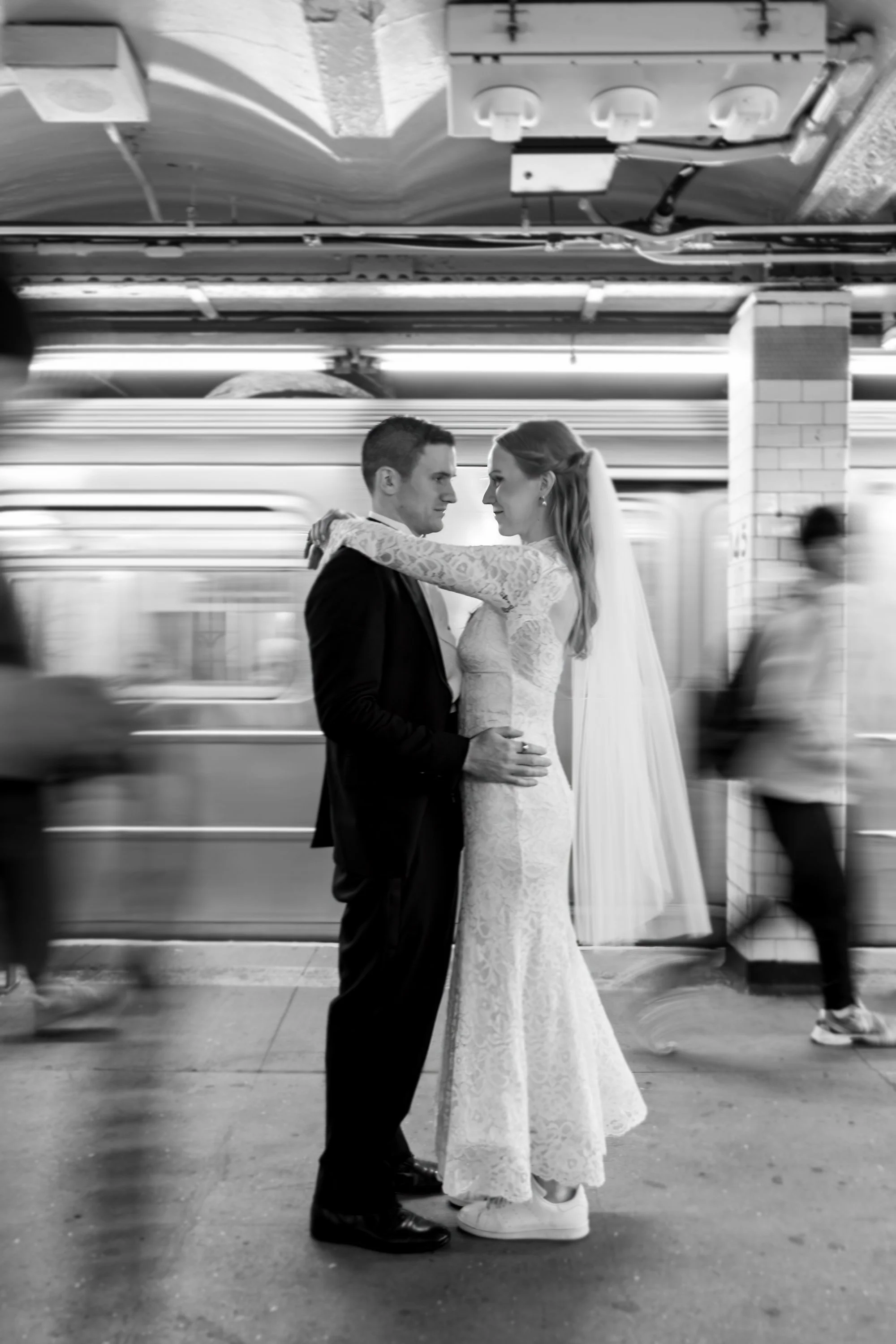 A newlywed couple gazing lovingly at each other while the subway and commuters walk past them

NYC wedding photographer