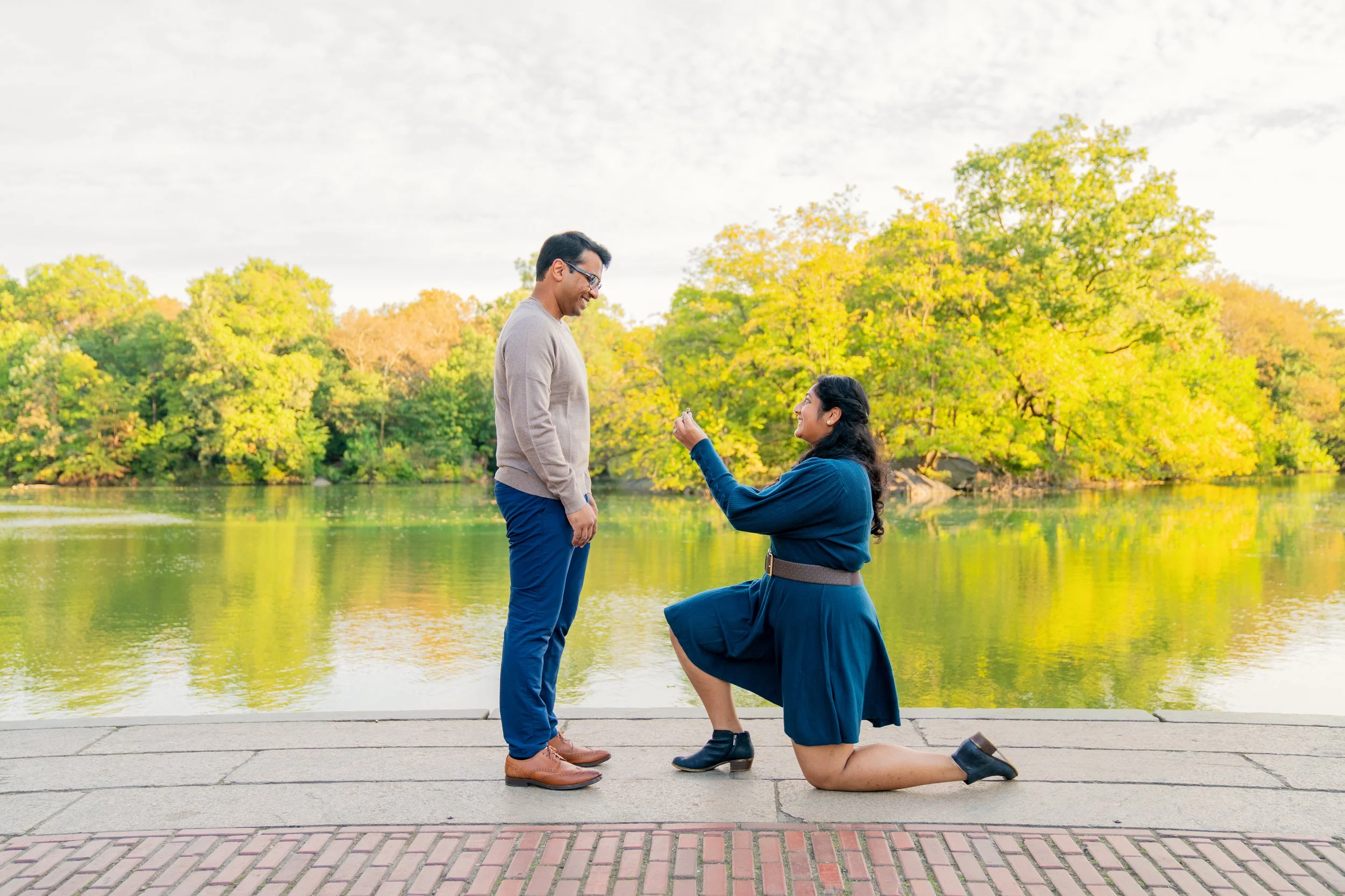 A smiling woman on one knee, proposing to her boyfriend