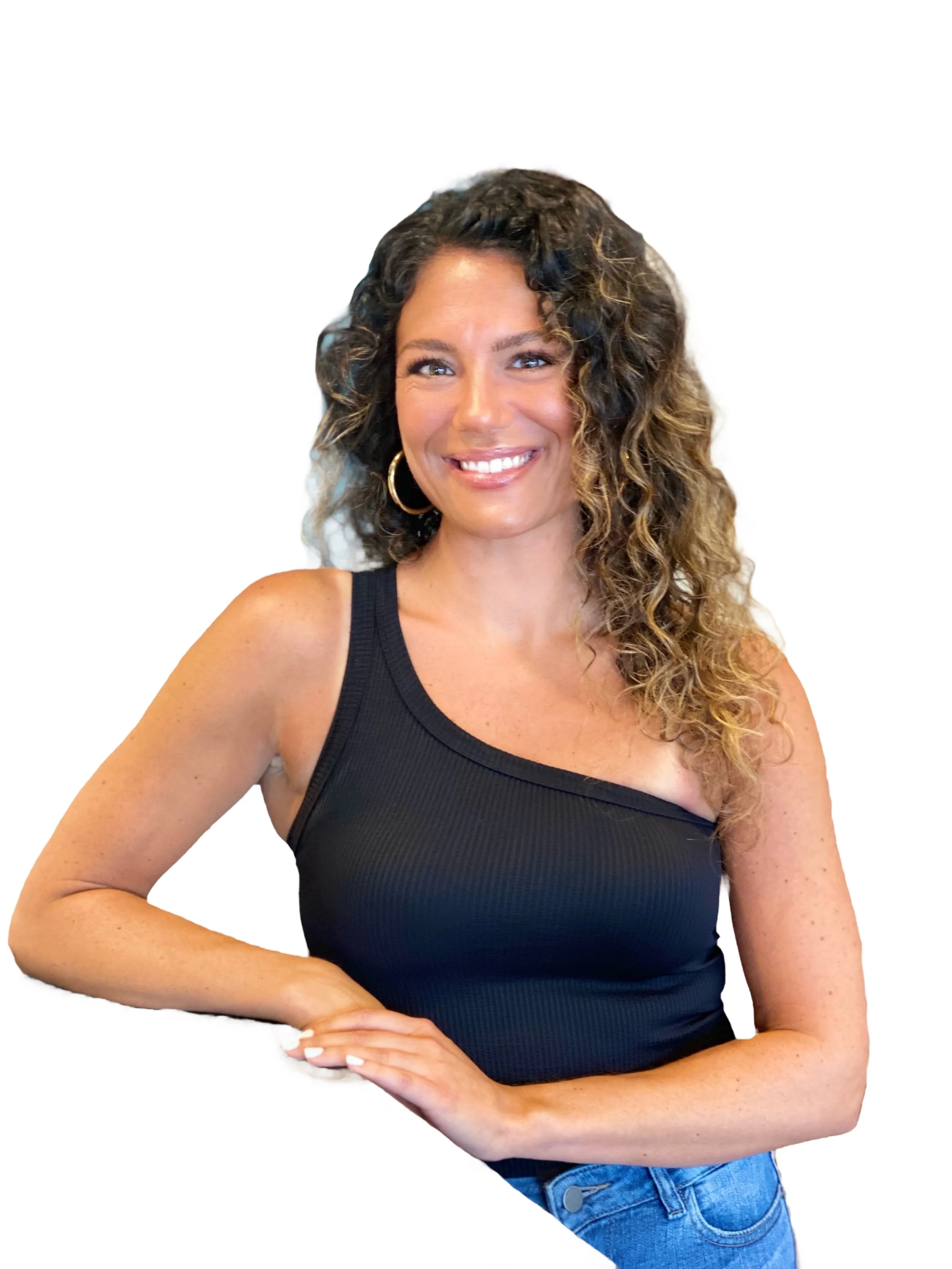 Smiling woman with shoulder-length dark hair wearing a blue top in a lush green indoor or outdoor garden.