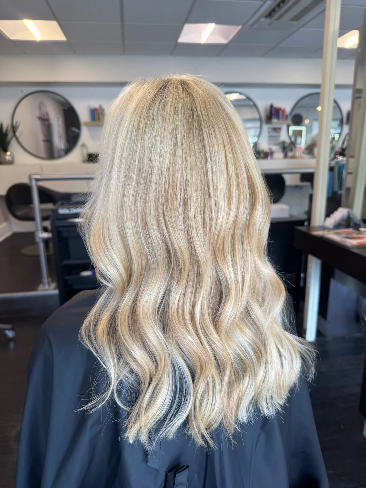 Blonde woman with wavy hair seated in a hair salon.