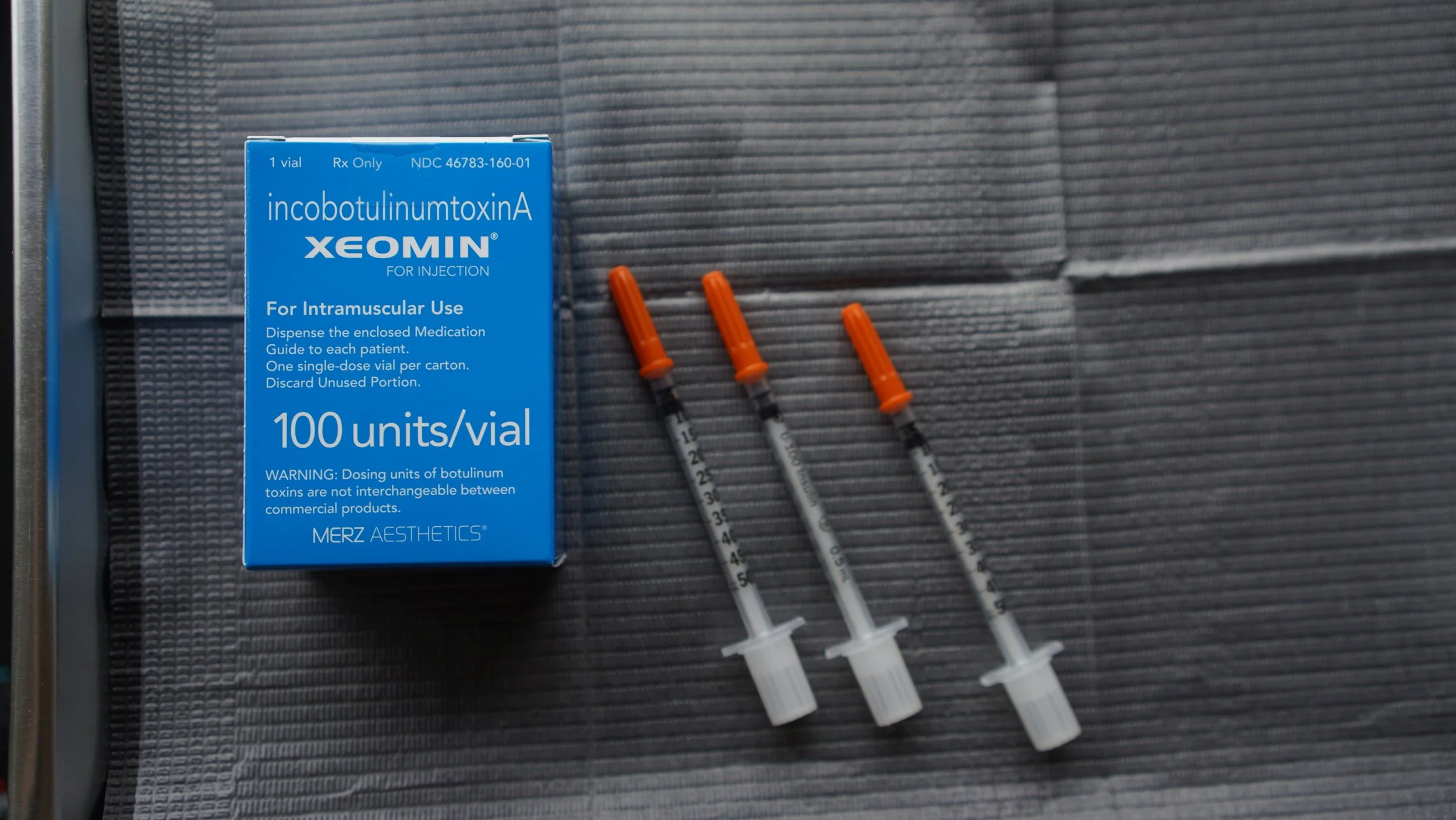 A person receiving a cosmetic injection in their cheek, with a healthcare professional wearing gloves preparing the syringe.