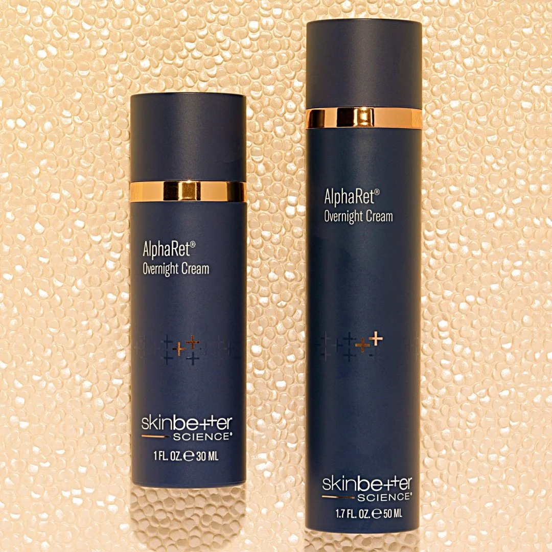 Two bottles of SkinBetter Science AlphaRet Overnight Cream, one small and one large, placed on a textured beige surface.