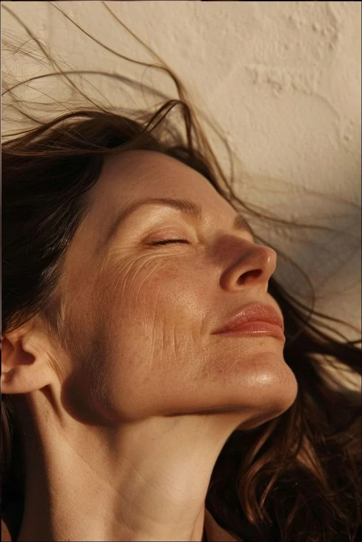 Close-up of a woman with closed eyes, smiling gently, with her head tilted back and her hair spread out.
