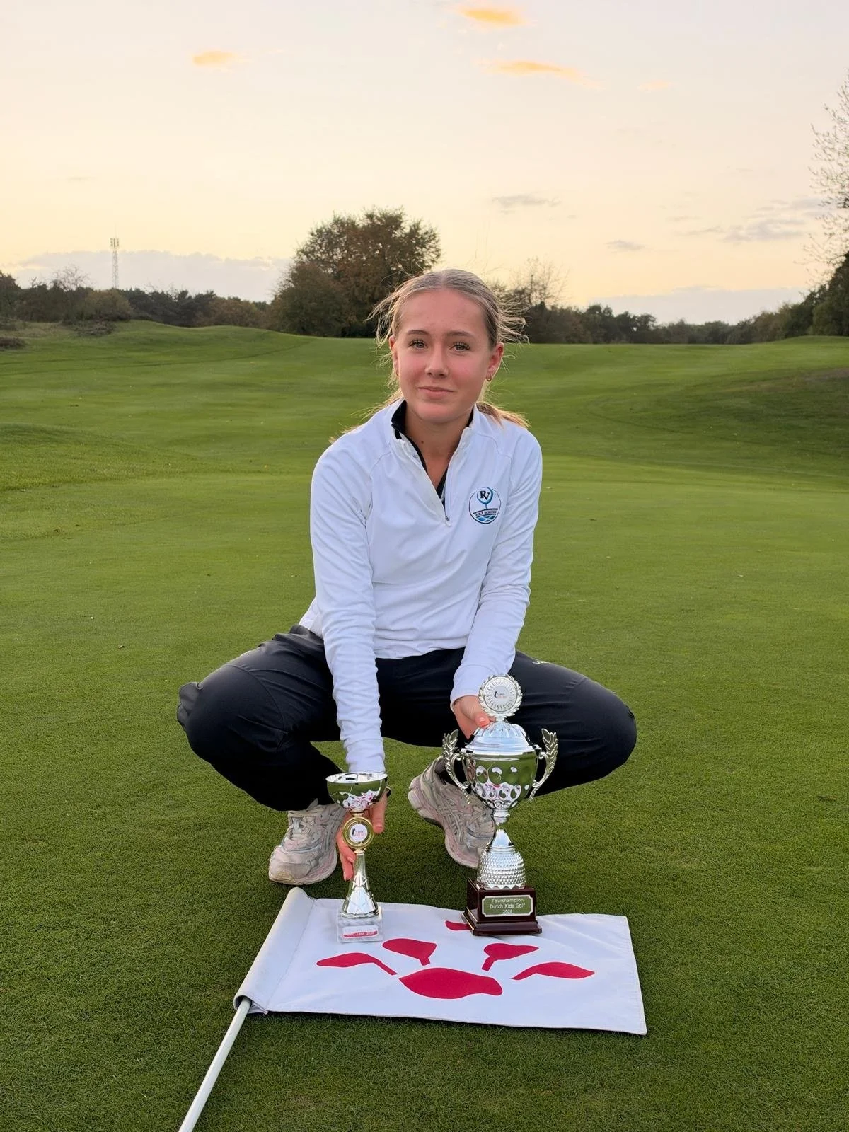 Ella-Louise with her golf trophies on a putting green